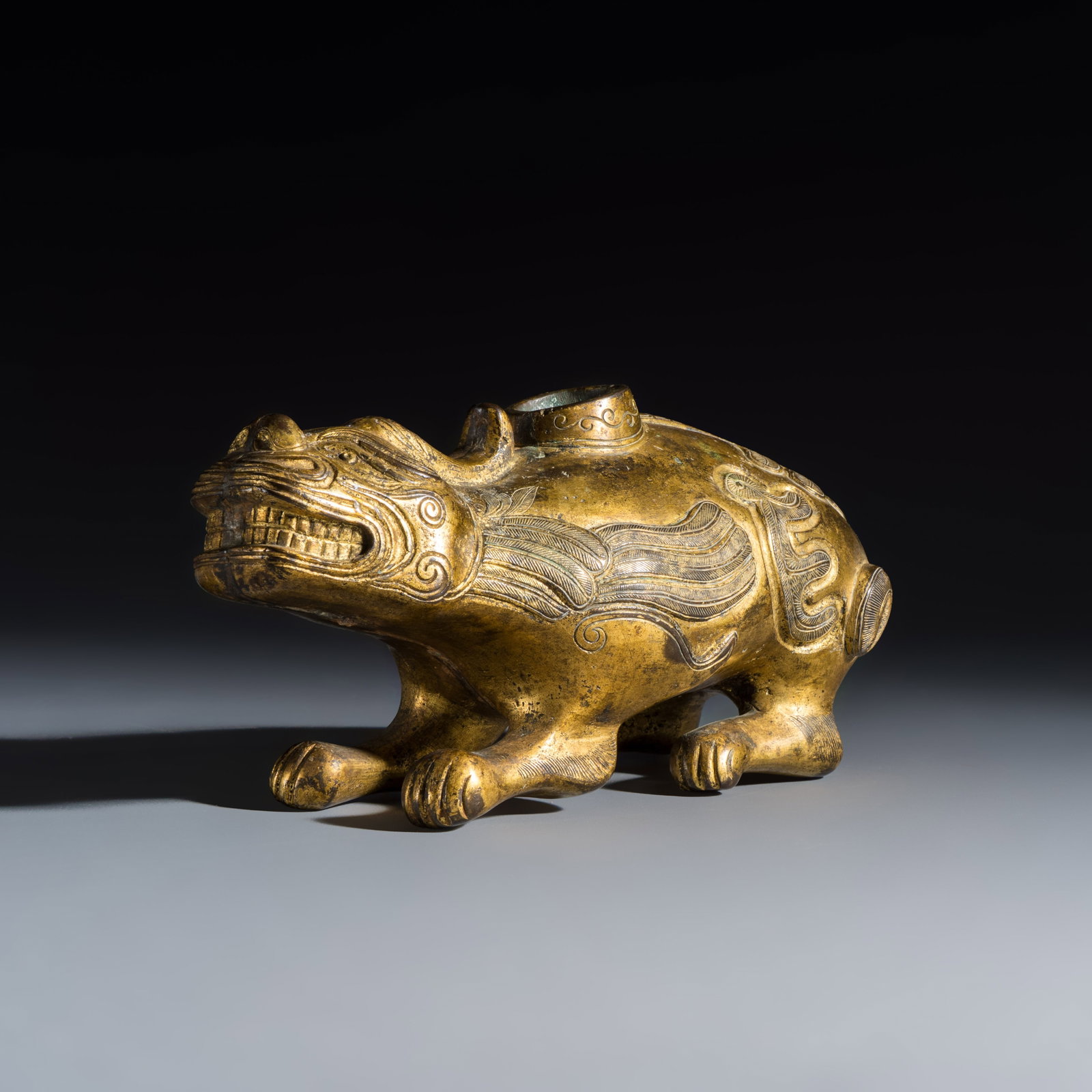 A Chinese gilt-bronze mythical beast-form water dropper, Ming: A Chinese gilt-bronze mythical beast-form water dropper, Ming Dim: 21,4 x 8,9 x 10,4 cm Weight: 2417 grams