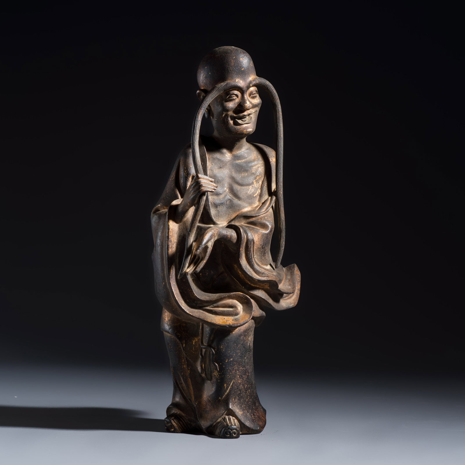 A Chinese inscribed lacquered gilt-bronze figure of a luohan, signed Li Yuan Dao Ren, Ming or: A Chinese inscribed lacquered gilt-bronze figure of a luohan, signed Li Yuan Dao Ren, Ming or earlier H.: 31,5 cm Weight: 3,7 kilograms