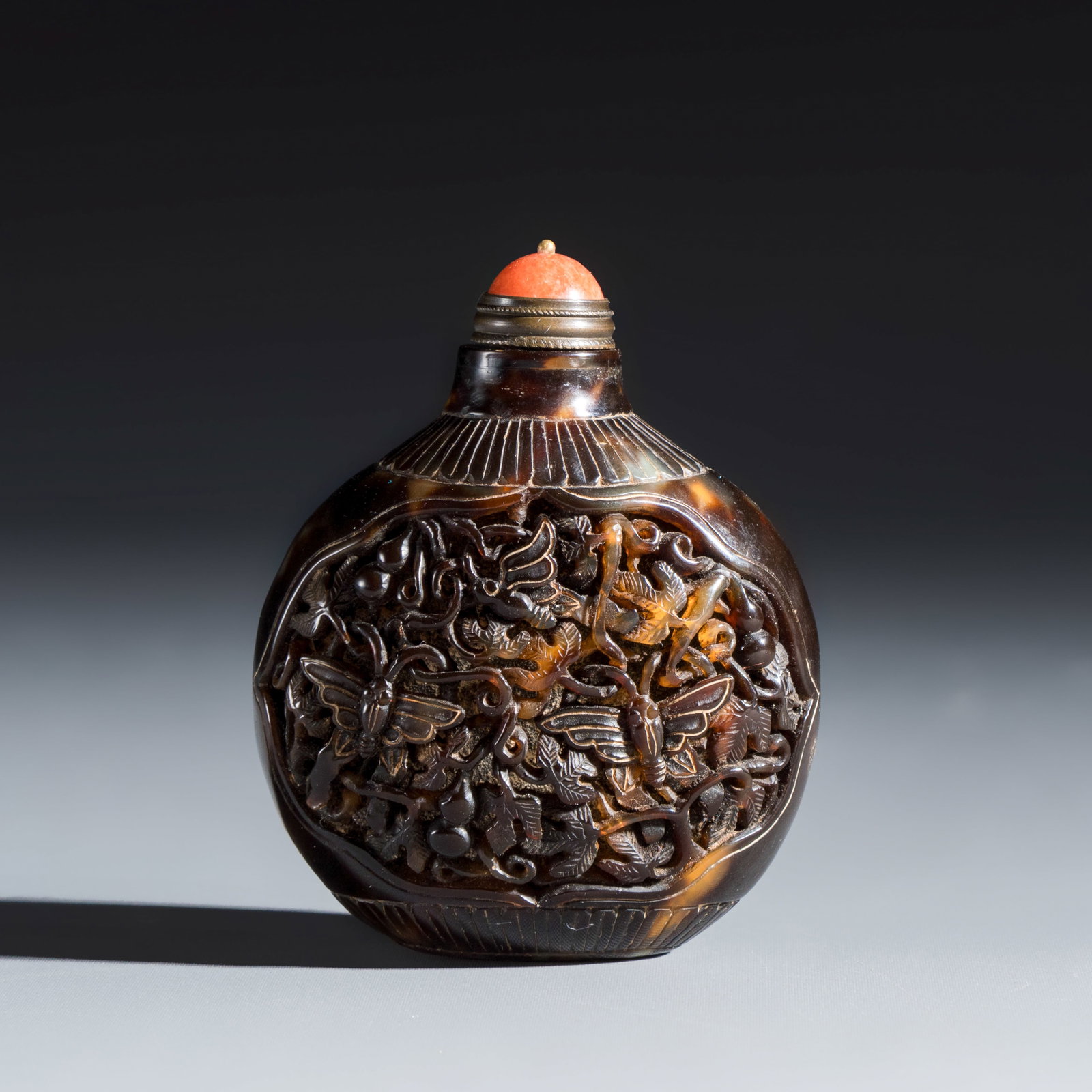 A Chinese carved tortoiseshell snuff bottle with butterflies among double-gourd vines, 19th C.: A Chinese carved tortoiseshell snuff bottle with butterflies among double-gourd vines, 19th C. H.: 7,8 cm | incl. stopper H.: 6,3 cm | excl. stopper