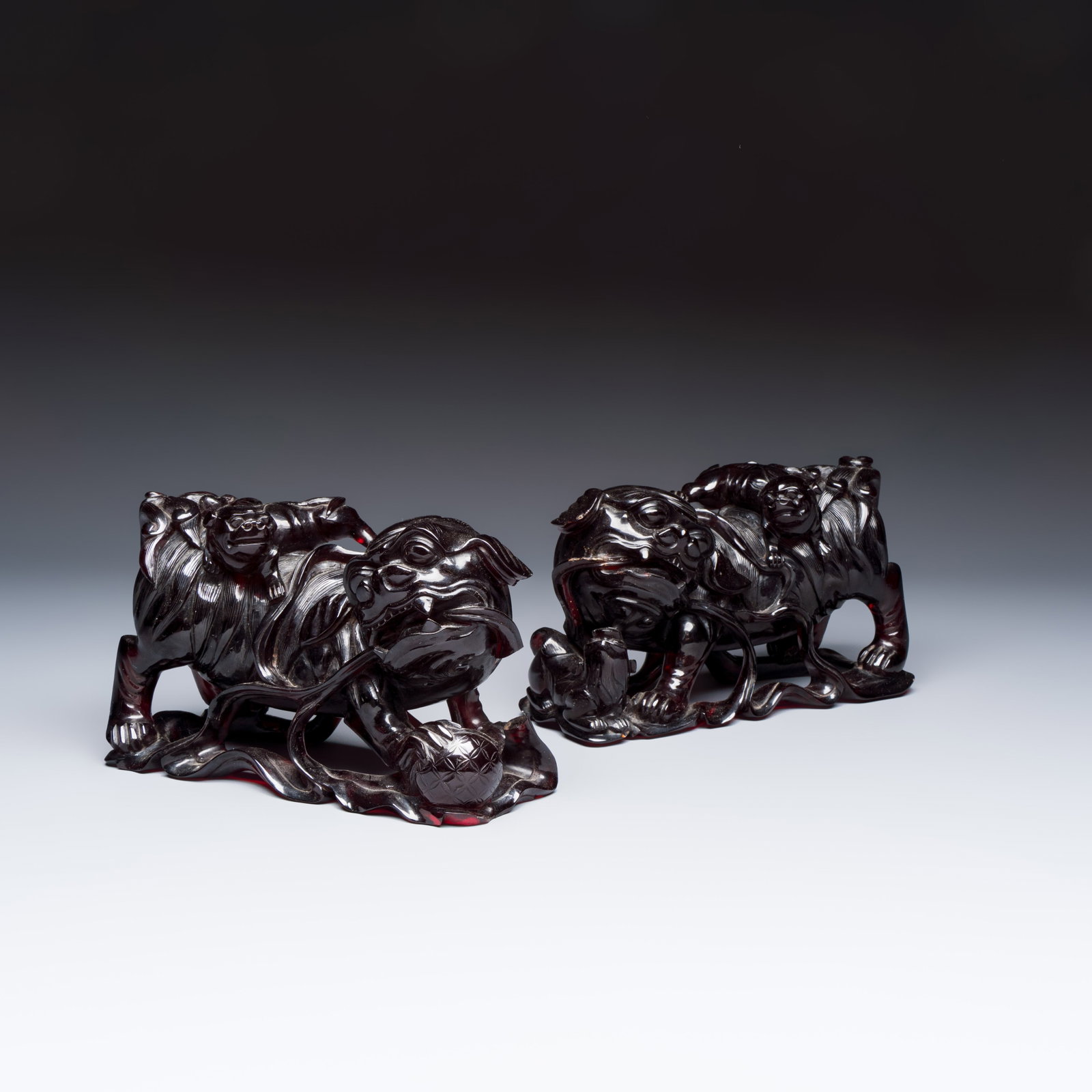 A pair of Chinese carved cherry amber 'Buddhist lions' groups, 20th C.: A pair of Chinese carved cherry amber 'Buddhist lions' groups, 20th C. Dim: 19,9 x 8,2 x 12 cm Total weight: 2092 grams