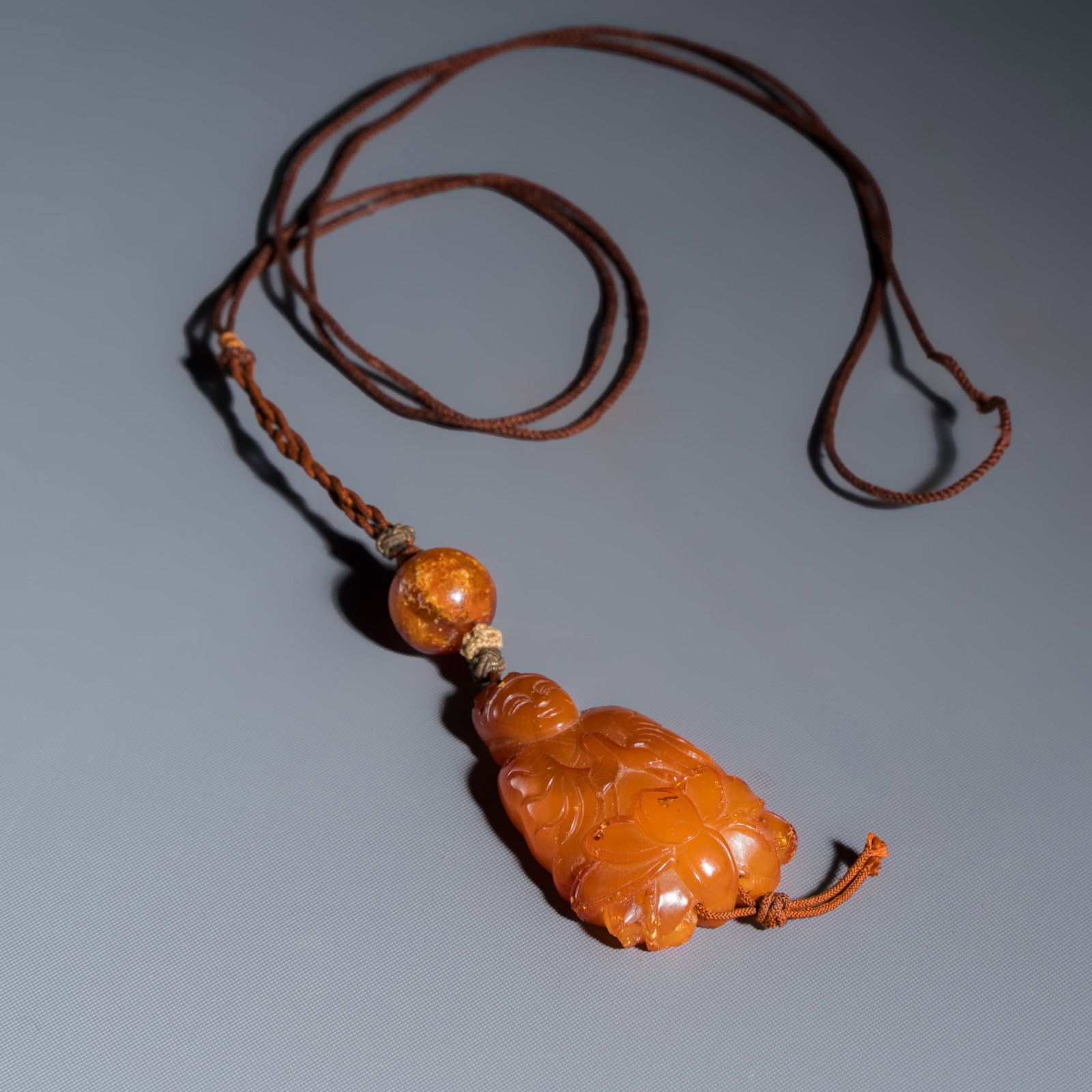 A Chinese carved amber pendant of a Bodhisattva, Qing: A Chinese carved amber pendant of a Bodhisattva, Qing Dim: 4,4 x 2,5 cm | the pendant, excl. cord Total weight: 8,97 grams