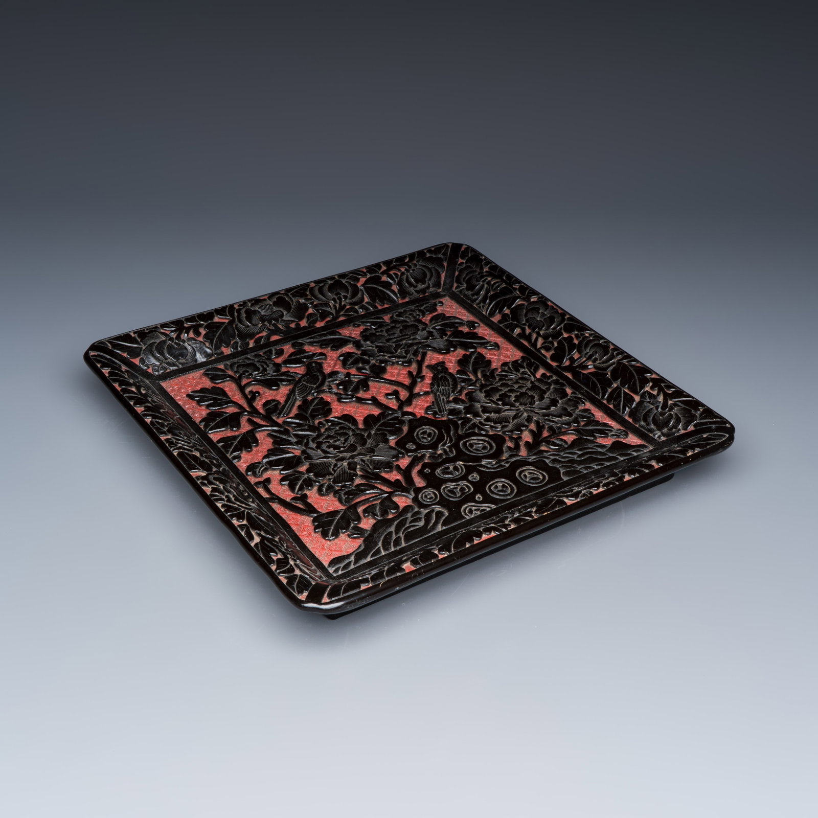 A Chinese carved red and black cinnabar lacquer square tray, Qing: A Chinese carved red and black cinnabar lacquer square tray, Qing Dim: 35 x 34,4 x 4,9 cm Ref.: Bonhams, London, 15 March 2021, lot 125, for a near-identical example (sold USD 4.080)