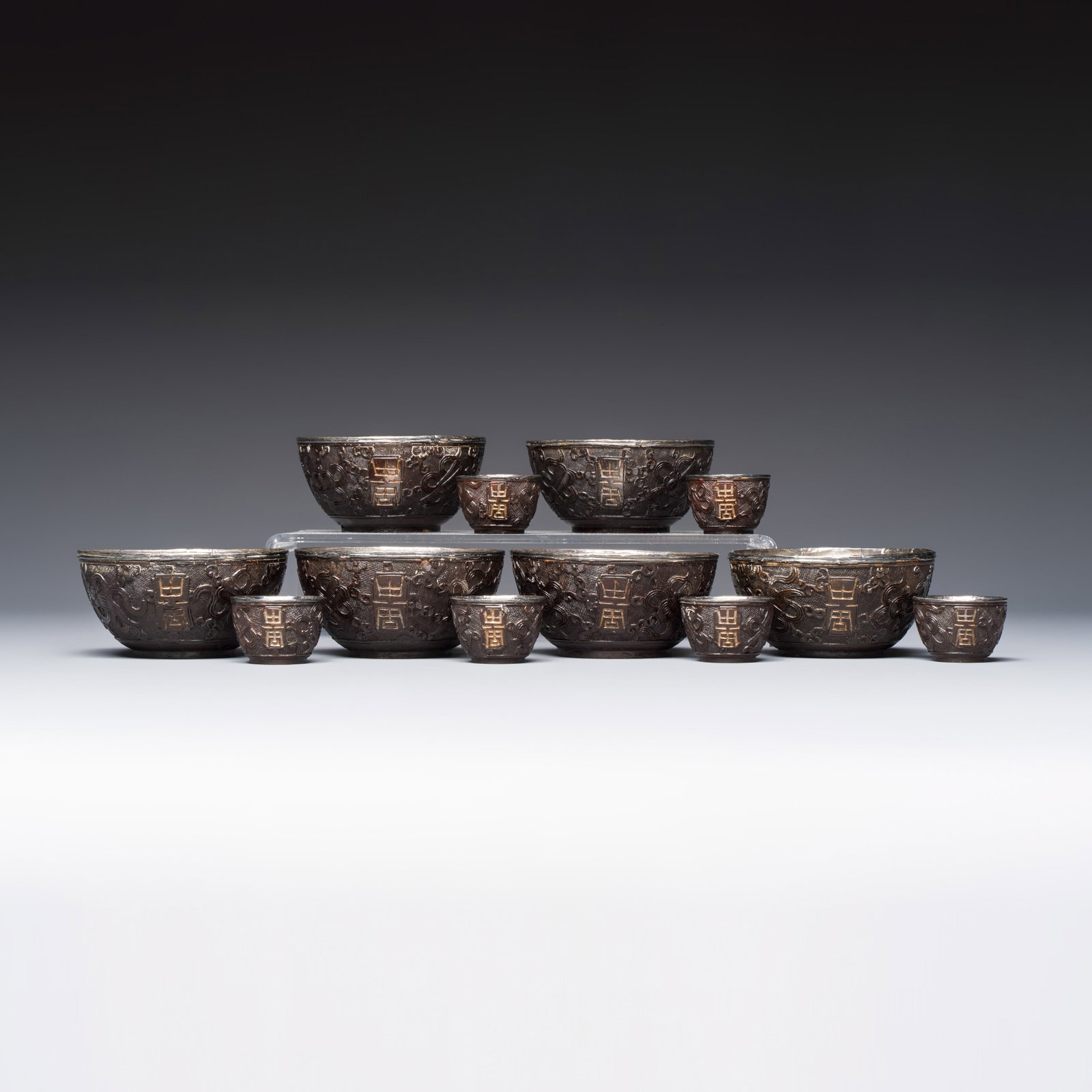 A group of 12 Chinese silver-lined coconut 'Shou' bowls and cups, Wang Hengxin marks, 19/20th C.: A group of 12 Chinese silver-lined coconut 'Shou' bowls and cups, Wang Hengxin marks, 19/20th C. Dia.: 9 cm - H.: 4,5 cm | the bowls Dia.: 4 cm - H.: 2,5 cm | the cups