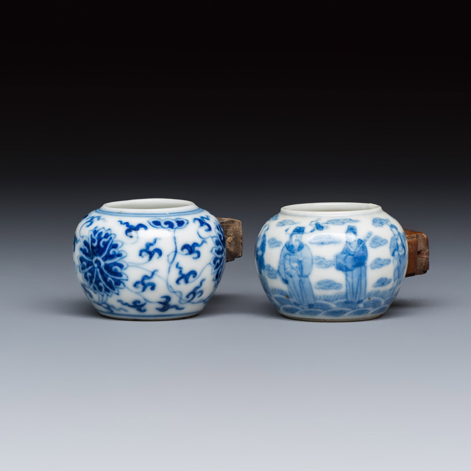Two Chinese blue and white bird feeders with lotus scroll design and the Eight Immortals, Qianlong: Two Chinese blue and white bird feeders with lotus scroll design and the Eight Immortals, Qianlong mark, 19th C. L.: 5,6 cm - H.: 3,3 cm