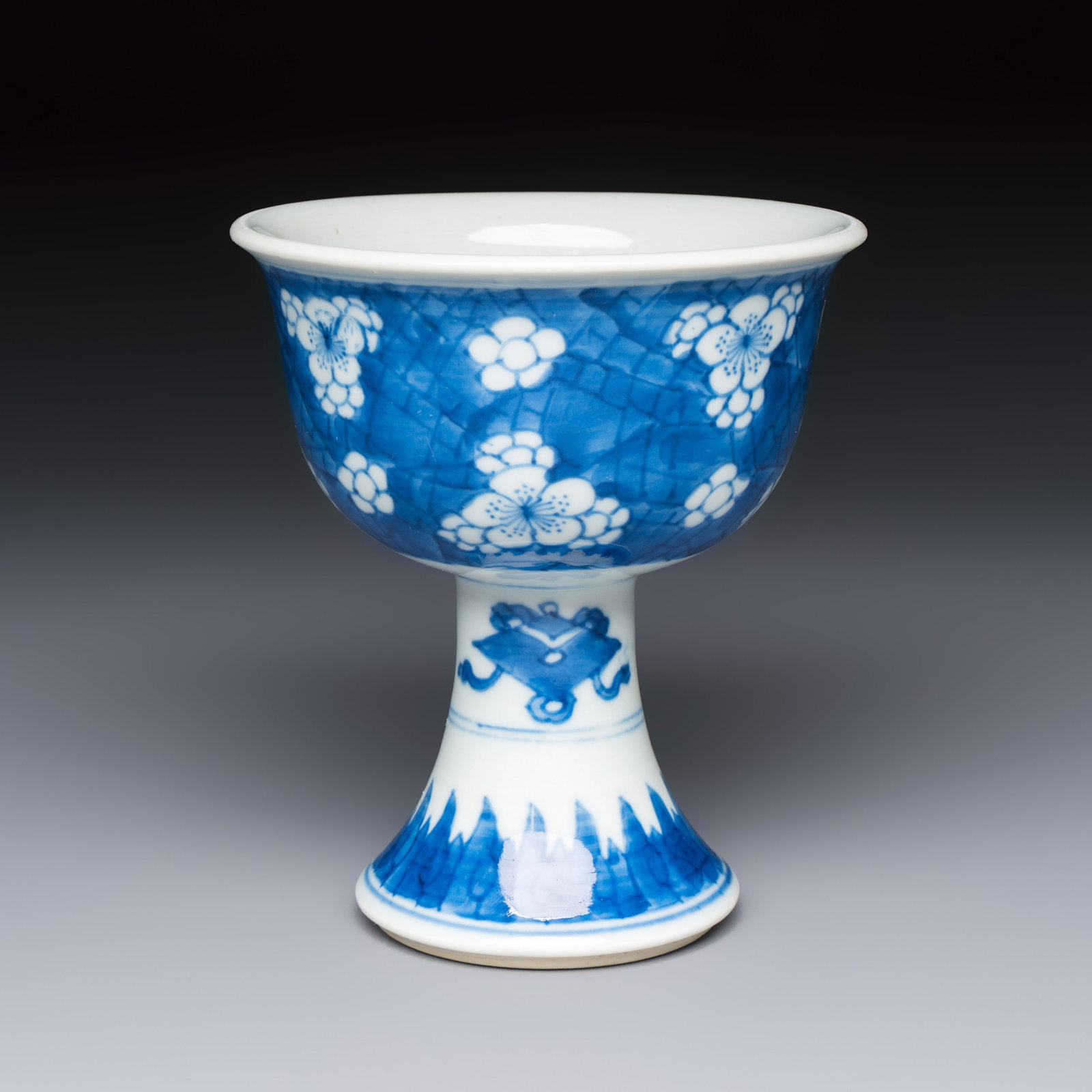 A Chinese blue and white 'Prunus on Cracked Ice' stem bowl, Kangxi: A Chinese blue and white 'Prunus on Cracked Ice' stem bowl, Kangxi Dia.: 11 cm - H.: 12,3 cm With a label from Hamadi Oriental Art, Hattem, the Netherlands.