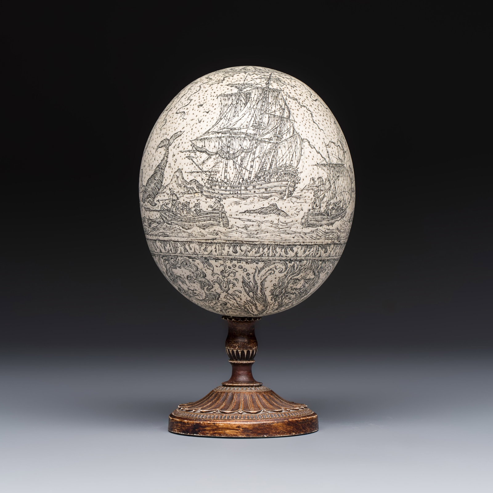 An engraved ostrich egg with a maritime scene on a wooden stand, 20th C. (1 of 6)