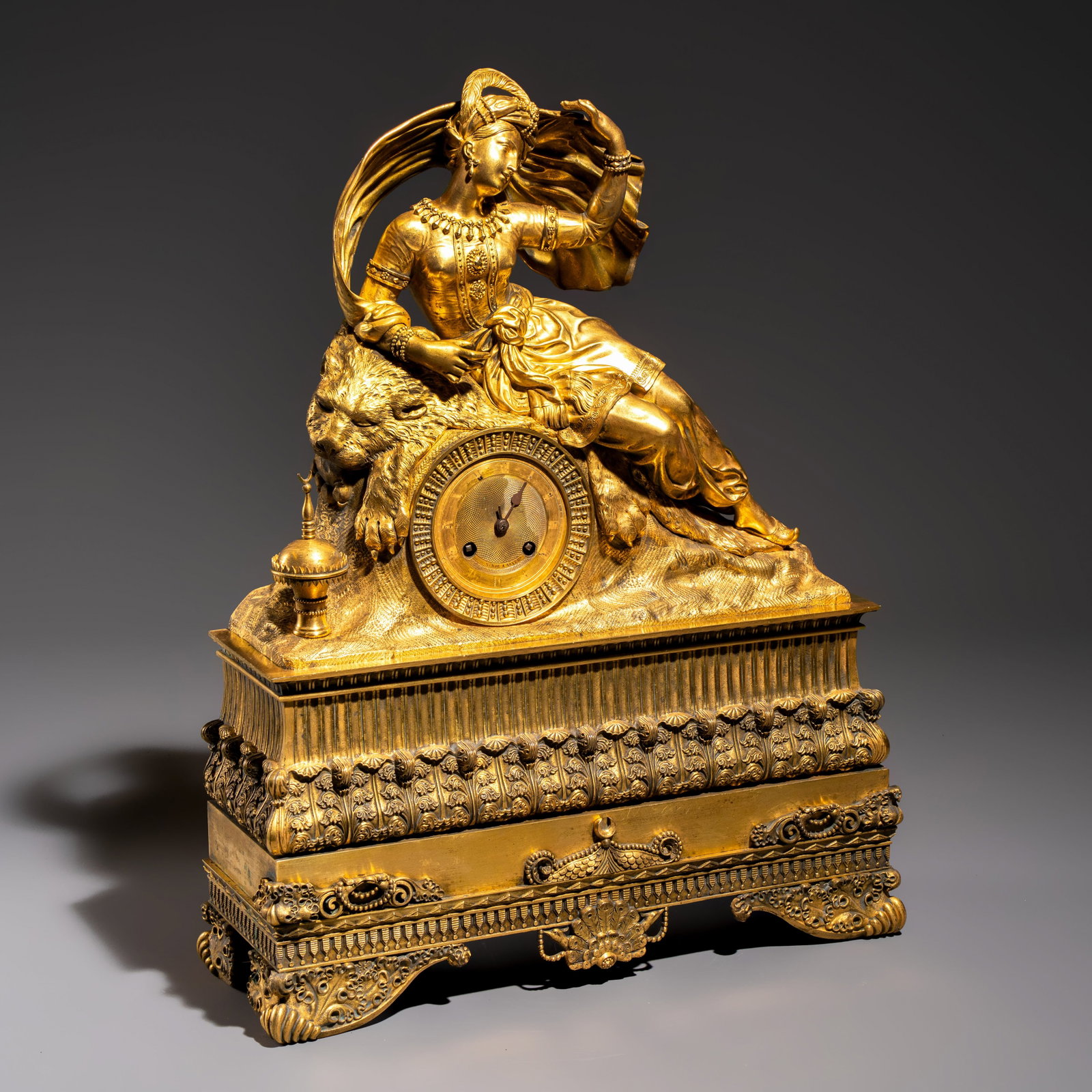 A gilt-bronze 'Oriental Beauty Reclining on a Lion Skin' mantel clock, France, first quarter 19th C.: A gilt-bronze 'Oriental Beauty Reclining on a Lion Skin' mantel clock, France, first quarter 19th C. Dim: 40,5 x 14 x 52 cm Weight: approx. 10,9 kilograms