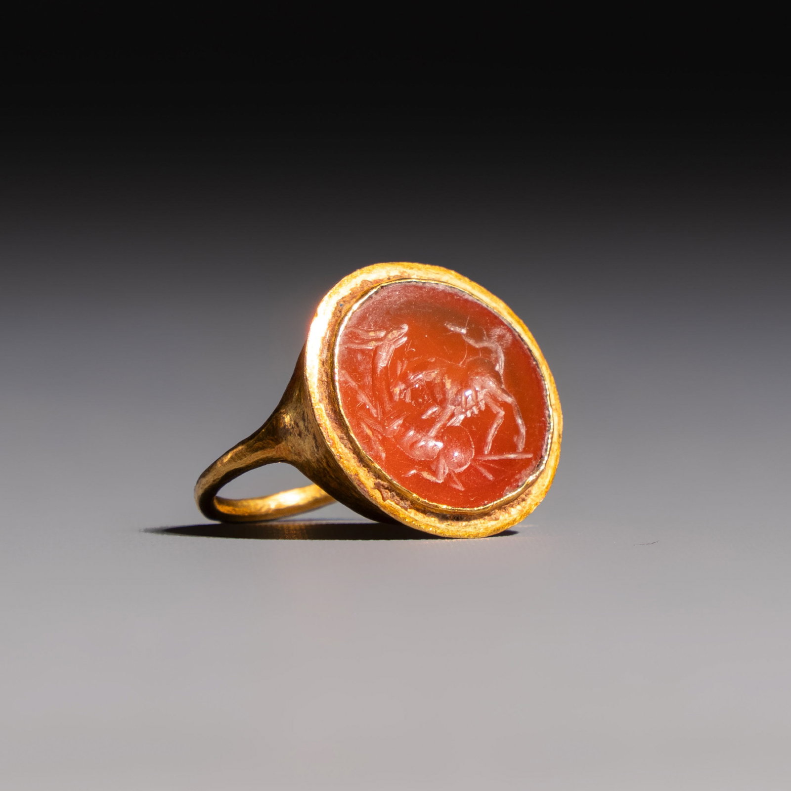 A carnelian intaglio depicting a wolf attacking a stag, set in a gold ring, Roman and later: A carnelian intaglio depicting a wolf attacking a stag, set in a gold ring, Roman and later Dim: 1,7 x 1,7 x 1,9 cm weight: 2,8 grams