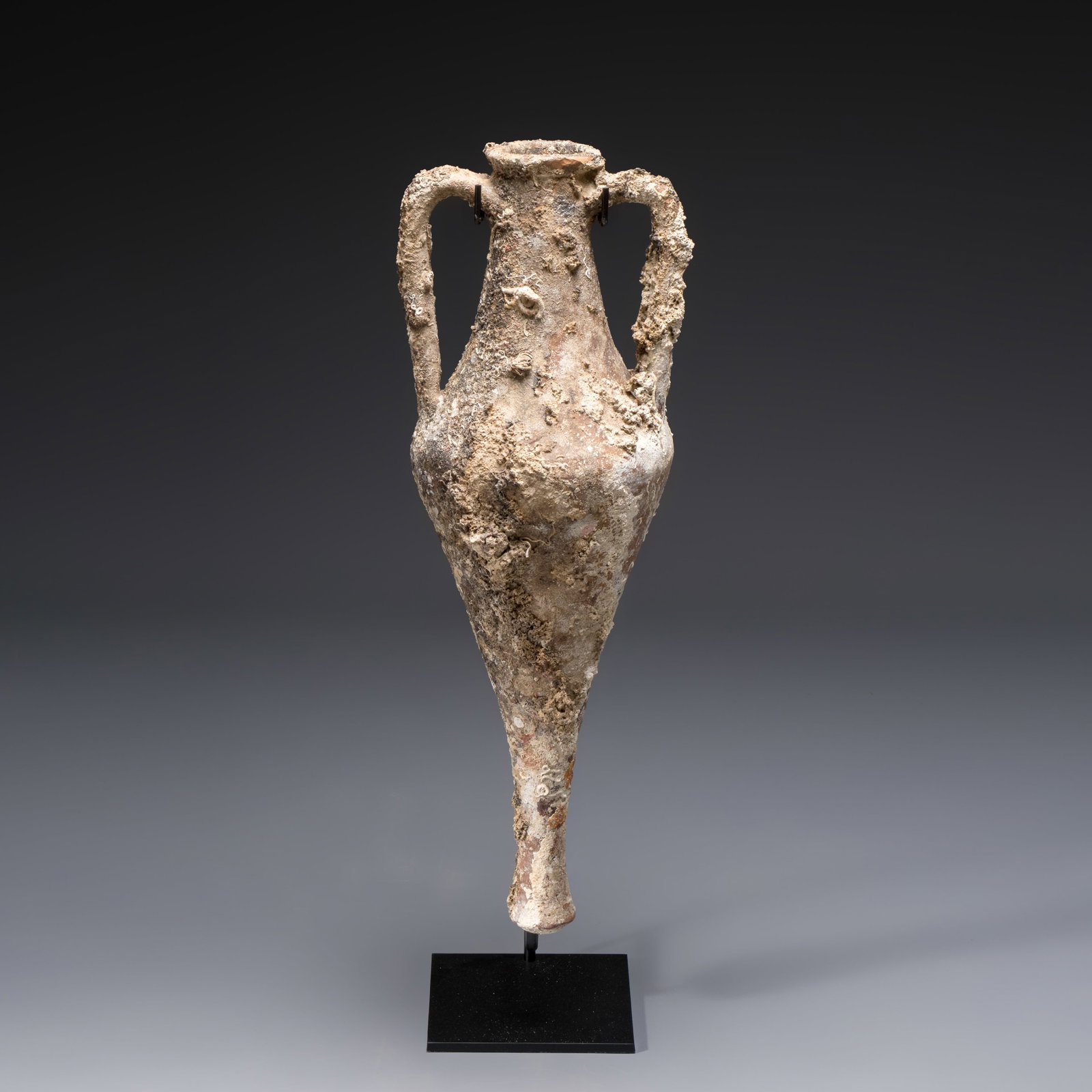 An early Greek pottery wine transport amphora with marine encrustation, Ancient Macedonia, 6/4th C.: An early Greek pottery wine transport amphora with marine encrustation, Ancient Macedonia, 6/4th C. B.C. H.: 86 cm | incl. stand H.: 75 cm | excl. stand Provenance: Part of an important Belgian privat