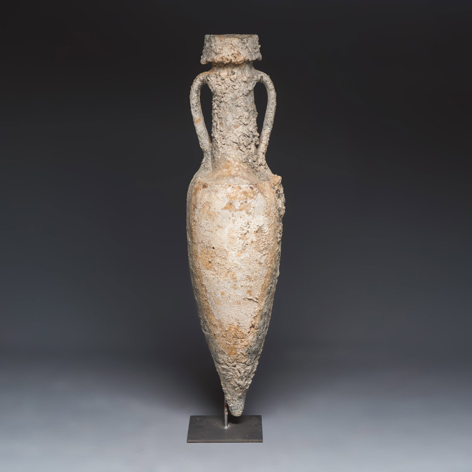 A very large Roman pottery wine transport amphora with marine encrustation, Middle Tyrrhenian coast: A very large Roman pottery wine transport amphora with marine encrustation, Middle Tyrrhenian coast of Italy, 2nd/1st C. B.C. H.: 121,7 cm | incl. stand Provenance: Part of an important Belgian privat