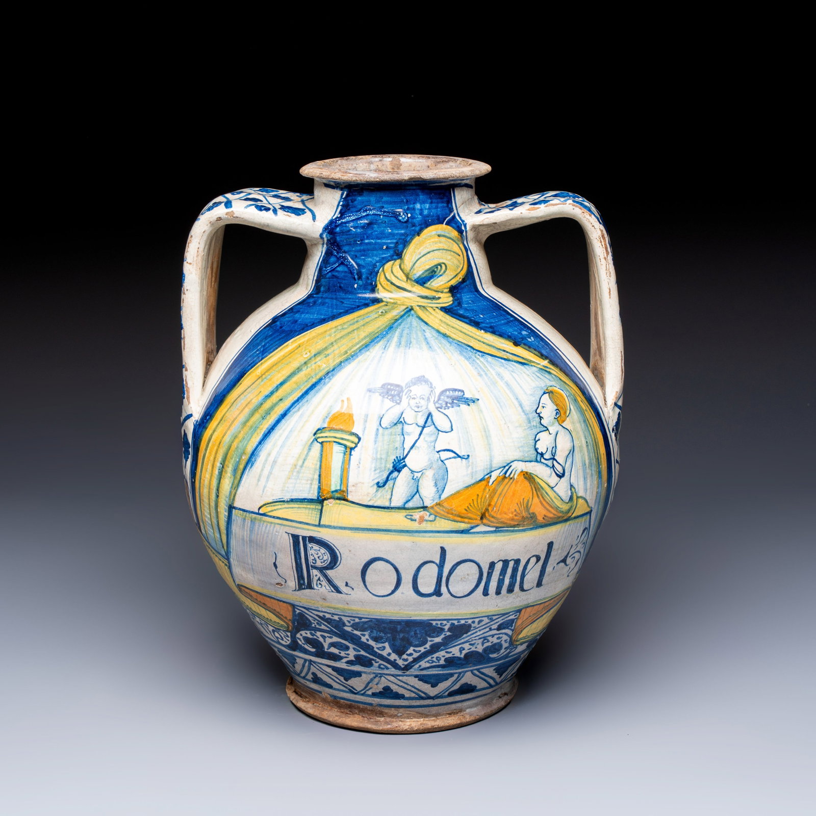 An unusual and large polychrome Italian maiolica two-handled 'Cupid and Psyche' wet drug jar: An unusual and large polychrome Italian maiolica two-handled 'Cupid and Psyche' wet drug jar inscribed 'Rodomel', probably Rome, early 16th C. H.: 34,5 cm Provenance: - A Belgian private collection, a