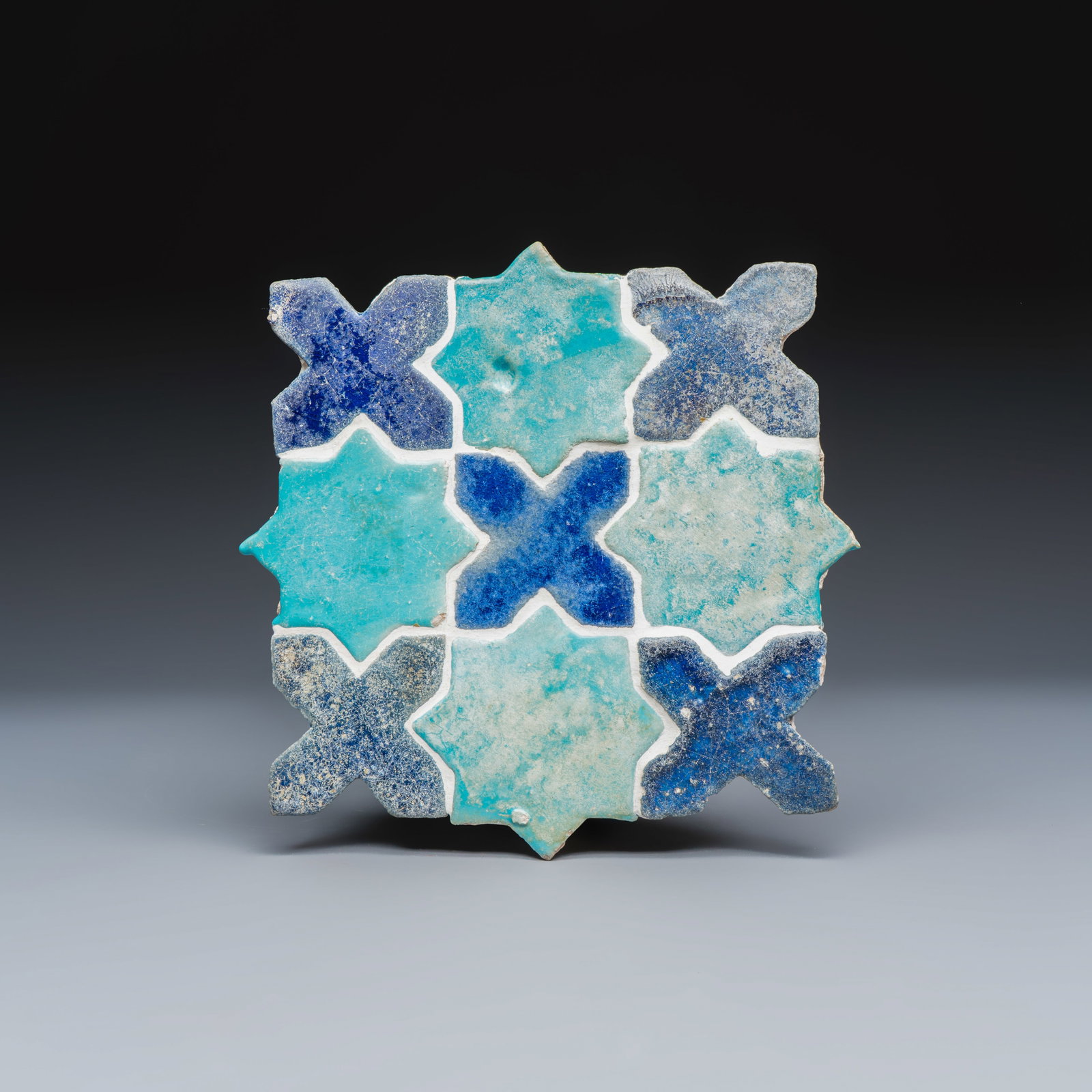 A panel of nine Kashan turquoise- and blue-glazed star and cross tiles, Persia, 12/13th C.: A panel of nine Kashan turquoise- and blue-glazed star and cross tiles, Persia, 12/13th C. Dim: 27,8 x 1,8 x 24 cm Provenance: A Belgian private collection. Rob Michiels Auctions, Nov. 26, 2011, lot 5
