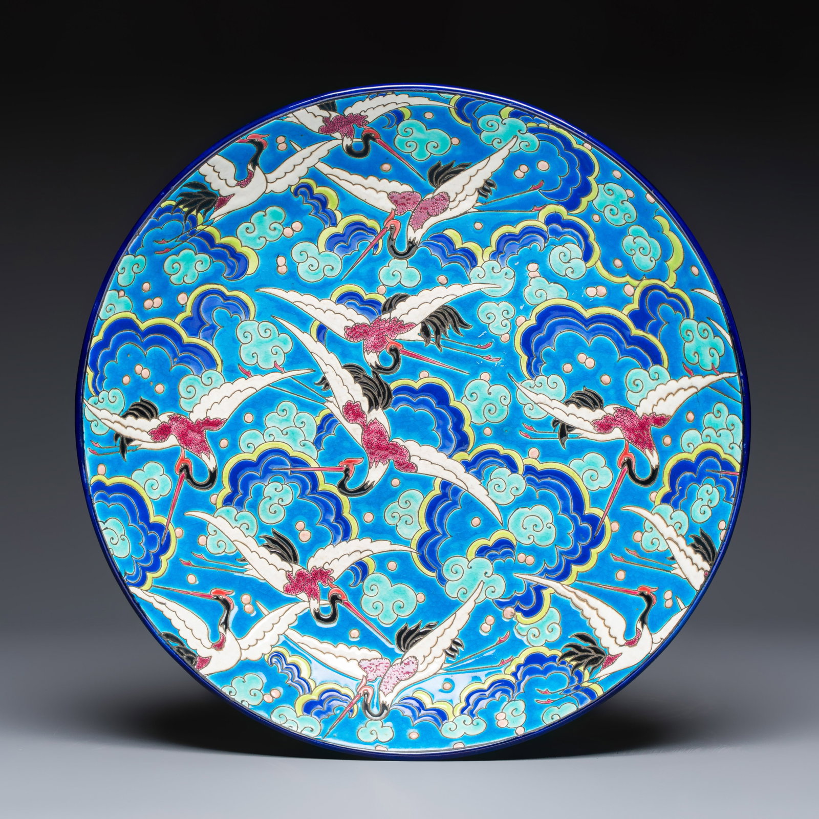 A French polychrome enamelled Longwy 'Cranes among Clouds' charger, 20th C. (1 of 2)