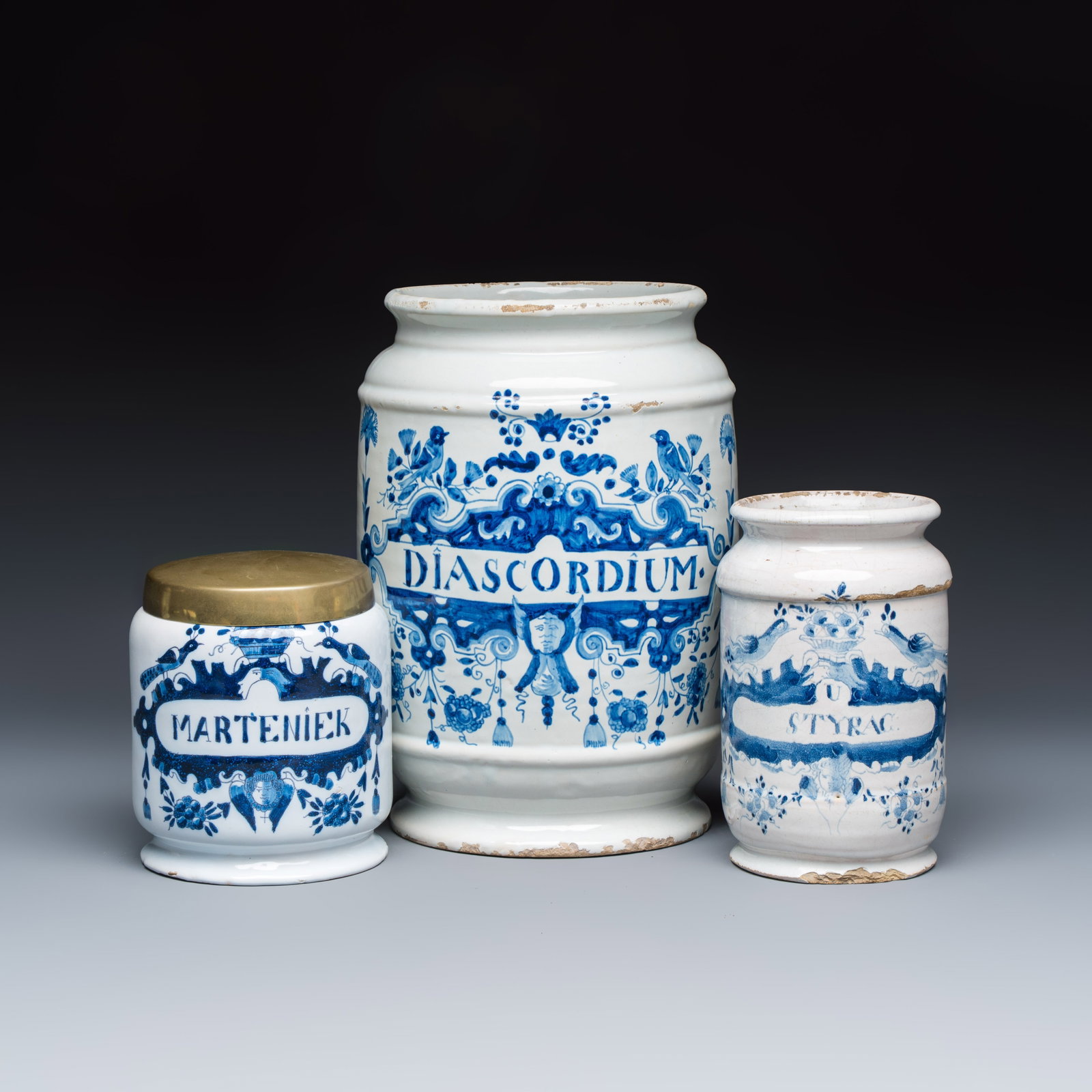A varied group of three Dutch Delft and Brussels faience apothecary jars, 18/19th C.: A varied group of three Dutch Delft and Brussels faience apothecary jars, 18/19th C. H.: 27,6 cm | the largest H.: 15,2 cm | the smallest, incl. cover Provenance: Van Nie and Winnubst Antiquairs, Amst