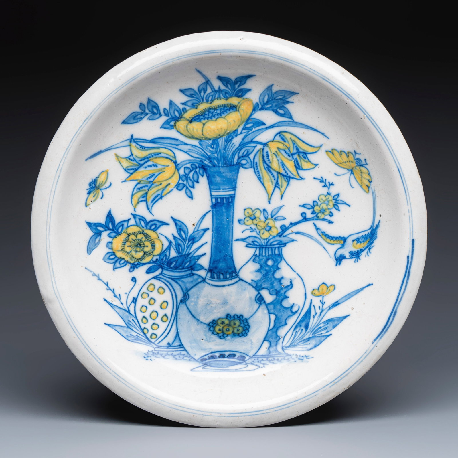 A polychrome Dutch Delft chinoiserie dish with flower vases, a bird and insects, 17th C. (1 of 2)