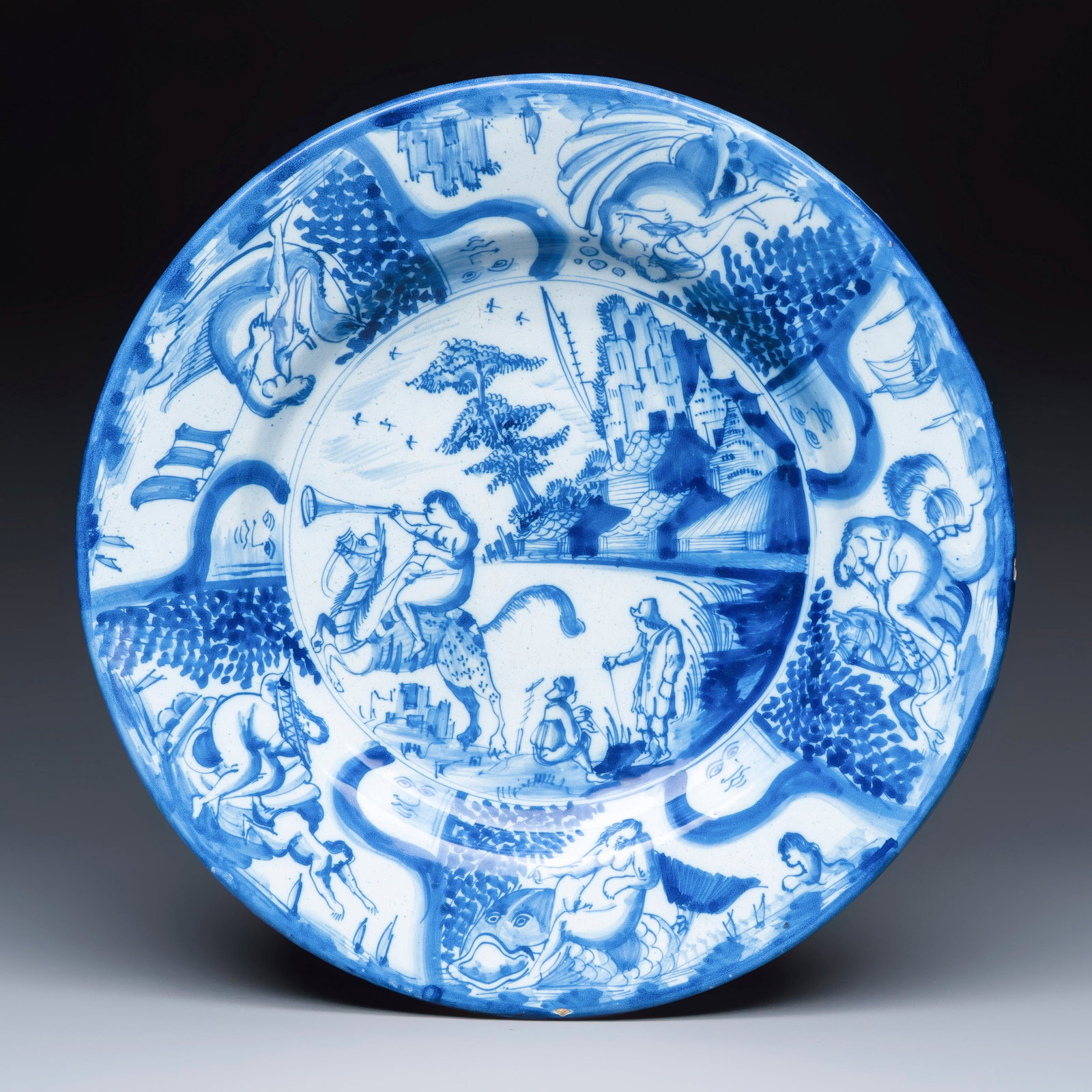 A large blue and white Dutch Delft mythological dish with a trumpet rider, 17th C. (1 of 2)
