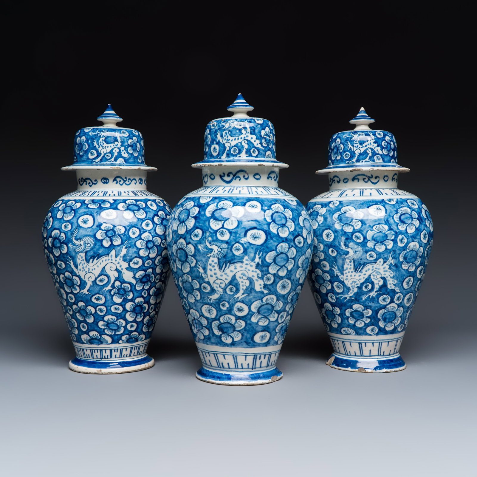 Three blue and white Dutch Delft vases and covers with dragons on a flowery ground, 18th C.: Three blue and white Dutch Delft vases and covers with dragons on a flowery ground, 18th C. H.: 38 cm | the tallest, incl. cover H.: 37,4 cm | the smallest, incl. cover