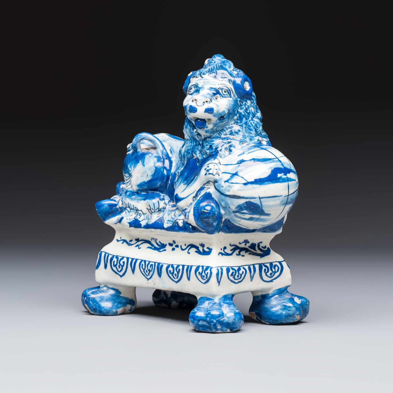 A blue and white Dutch Delft model of a recumbent lion holding a globe, 18th C.: A blue and white Dutch Delft model of a recumbent lion holding a globe, 18th C. H.: 18 cm Ref.: A comparable pair from the Lavino Collection is in the Kunstmuseum Den Haag, The Netherlands, object no.