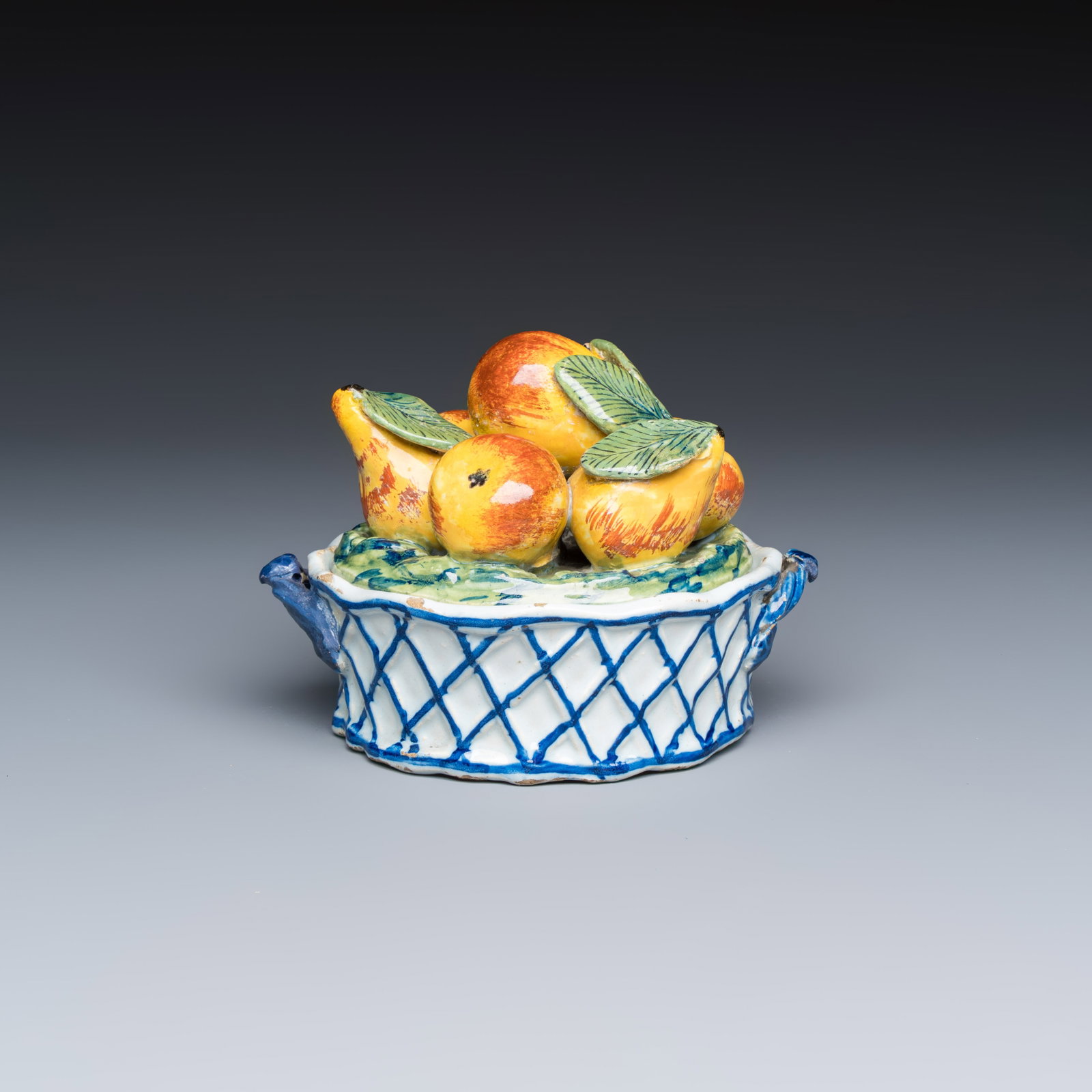 A polychrome Dutch Delft 'Fruit basket' butter tub and cover, 18th C.: A polychrome Dutch Delft 'Fruit basket' butter tub and cover, 18th C. L.: 12,9 cm - H.: 9,7 cm Each inscribed with a numeral 5, the tub marked with an axe for the 'De Porceleyne Byl' workshop, Delft.
