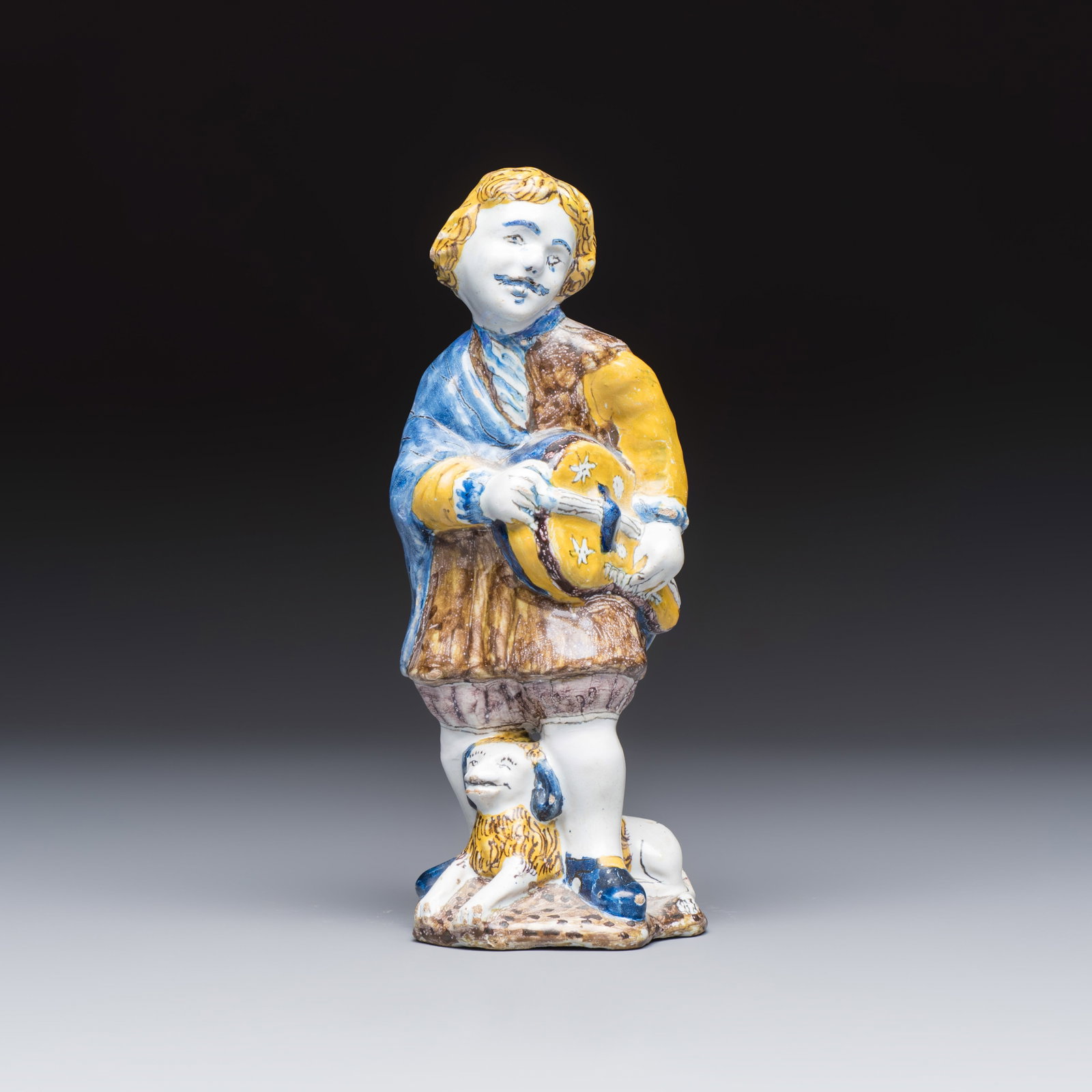A polychrome Dutch Delft figure of a hurdy-gurdy player with a dog, 18th C.: A polychrome Dutch Delft figure of a hurdy-gurdy player with a dog, 18th C. H.: 21 cm