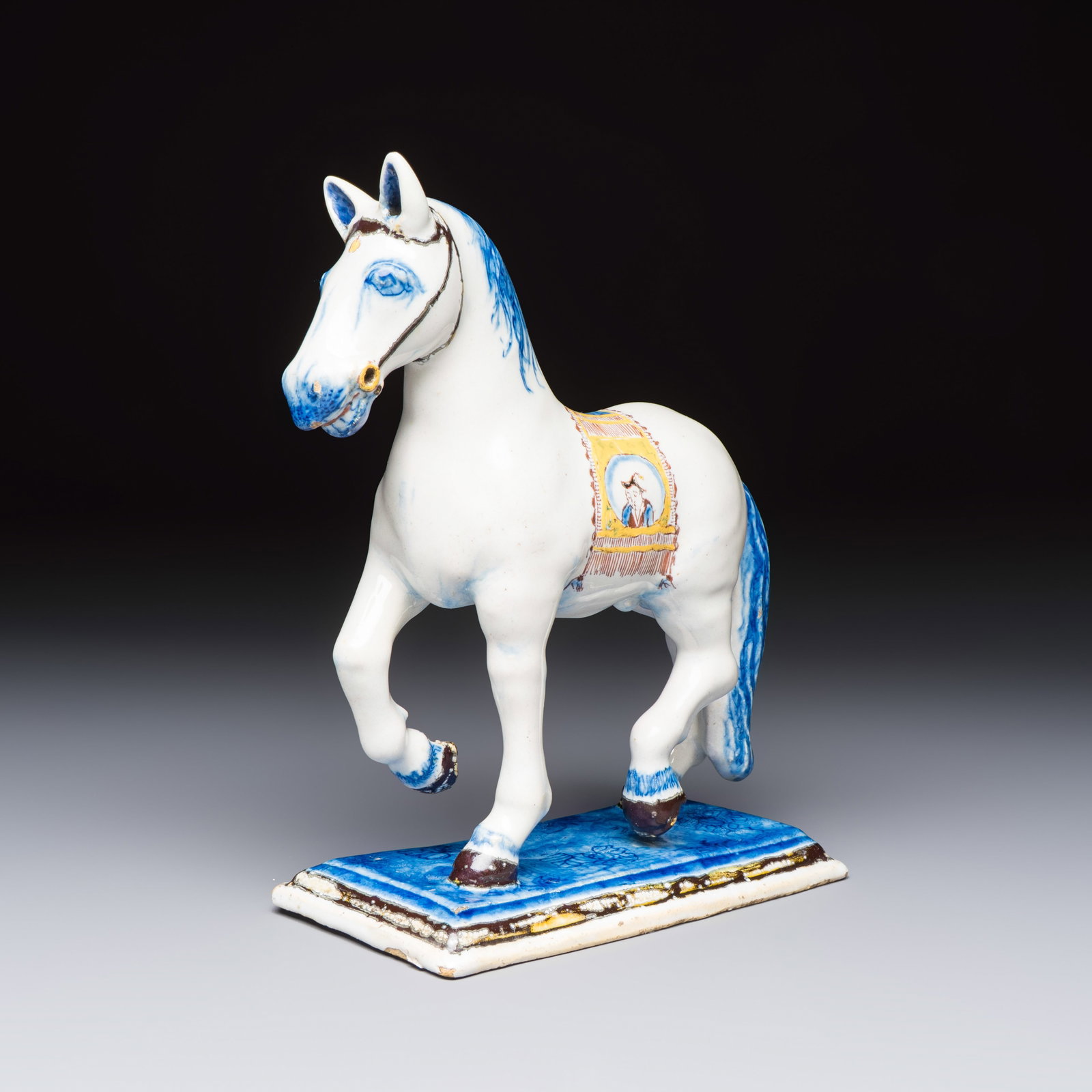 A polychrome Dutch Delft model of a standing horse with a figurative saddle cloth, 18th C.: A polychrome Dutch Delft model of a standing horse with a figurative saddle cloth, 18th C. Dim: 14 x 7,6 x 19 cm