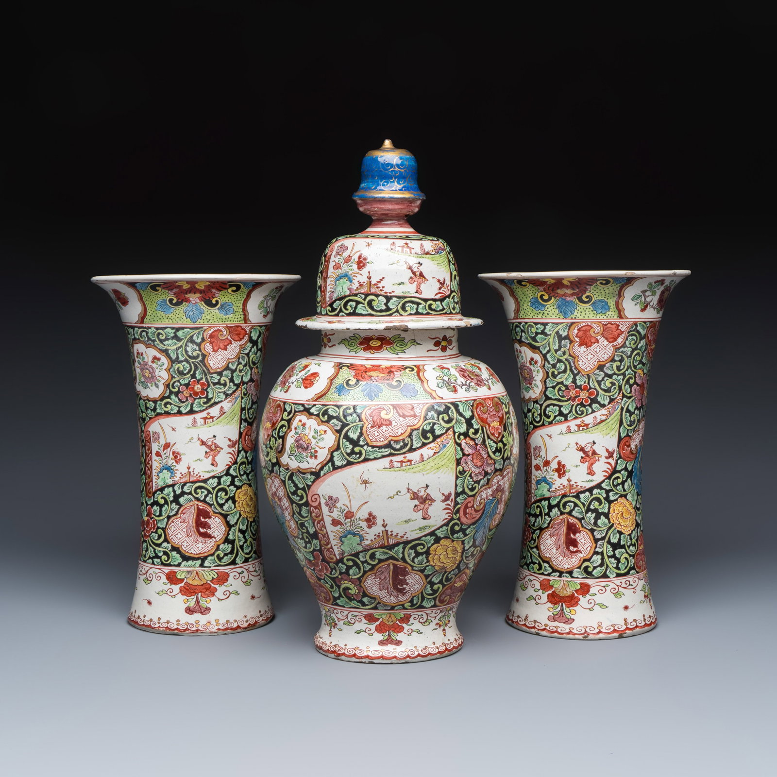 A polychrome petit feu Dutch Delft famille rose-style chinoiserie three-piece garniture, 18th C.: A polychrome petit feu Dutch Delft famille rose-style chinoiserie three-piece garniture, 18th C. H.: 36,7 cm | the tallest, incl. cover H.: 26,3 cm | the smallest