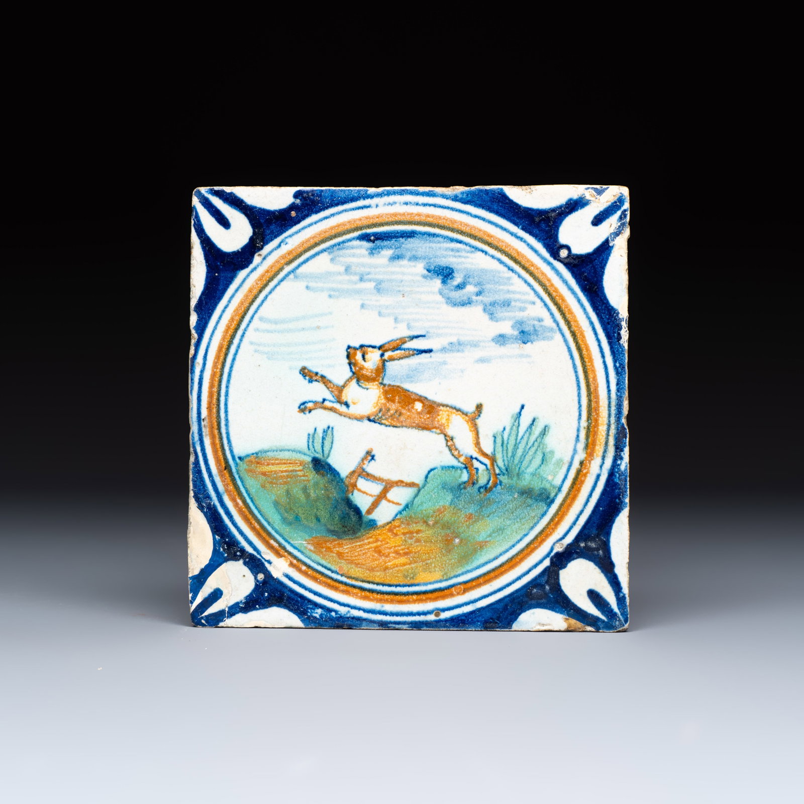 A polychrome Dutch Delft maiolica medallion tile with a leaping hare, 16th C. (1 of 2)