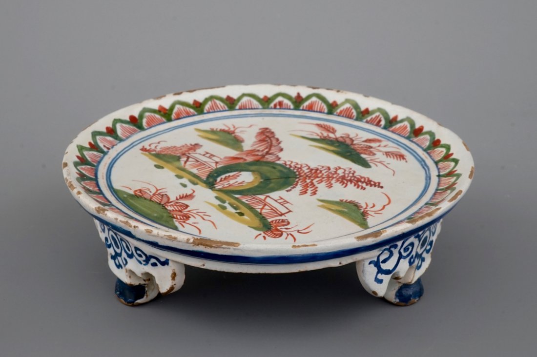A Dutch Delft tripod saucer in cashemire palette, ca.: H: 4 cm Dia.: 14,5 cm Condition: restored.