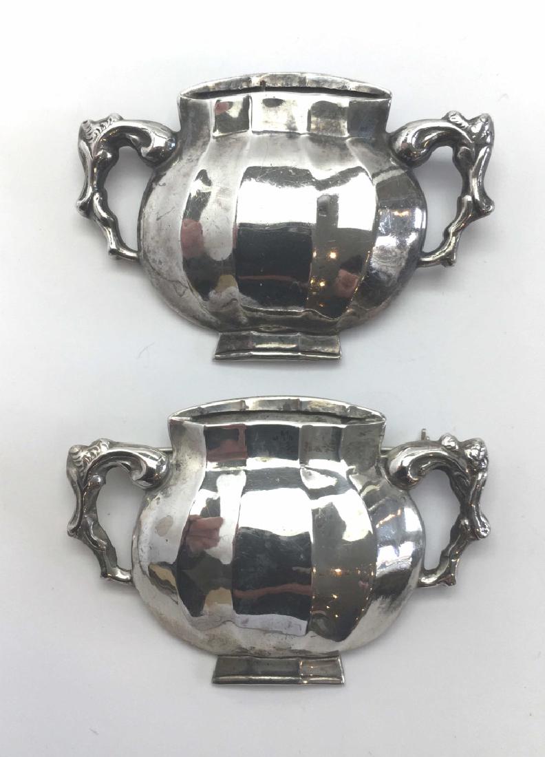 2 Stieff Sterling Williamsburg Loving Cup Brooches: A lovely pair of brooches made by Stieff in sterling silver in the 1940s or 50s for Colonial Williamsburg. Each measures 2 1/4" across. Signed both by Stieff and the Colonial Williamsburg restoration.
