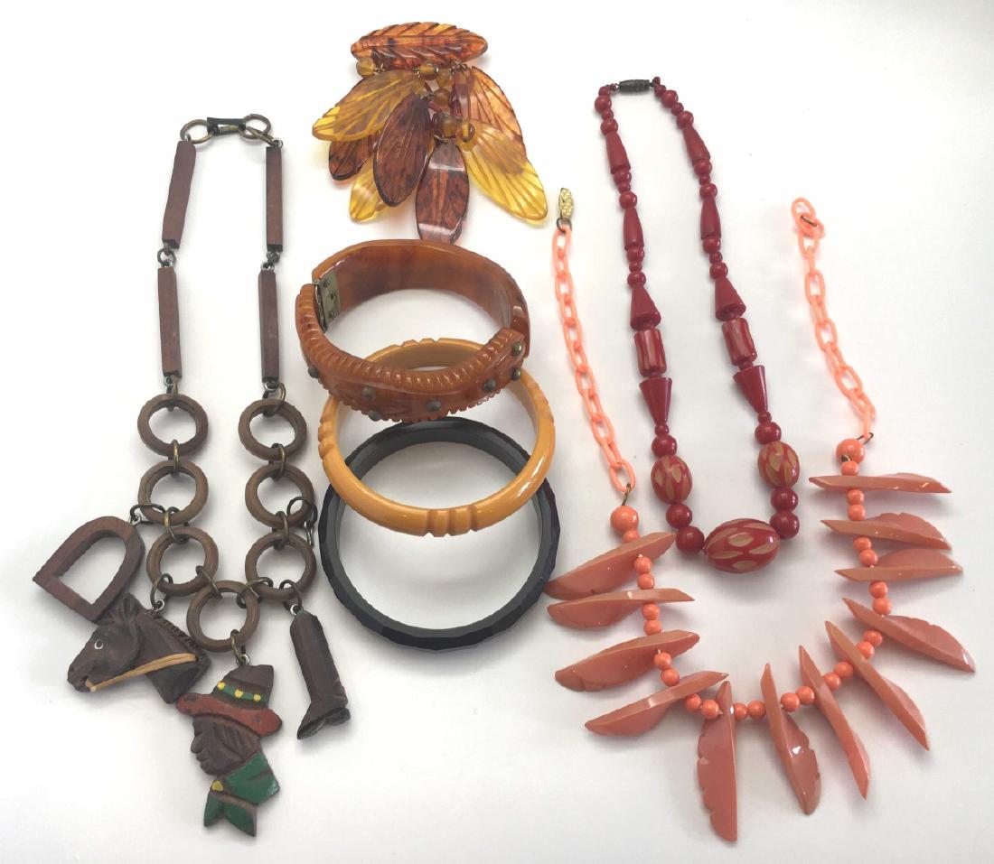 Carved Bakelite and Other Early Plastic Jewelry: Includes a carved and studded hinged bracelet, 2 bangles in yellow and brown, a carved dangling leaf pin - 4" long, a coral colored necklace - 17" long, a carved red necklace - 16" long and a carved w