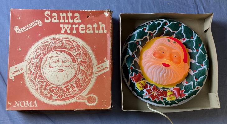 Illuminated Blow Mold Santa Wreath, Original Box: From Noma, catalog number 1130. The wreath measures approximately 12 1/2" in diameter. I found no flaws on the wreath. The box has some wear and damage as shown.
