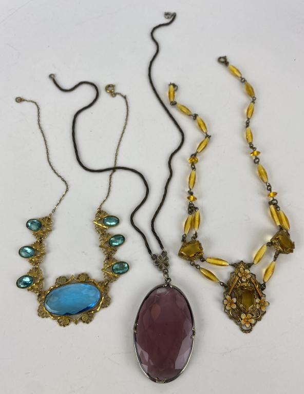 Three Czechoslovakian Crystal Art Deco Necklaces: Unmarked, these three necklaces appear to be Czechoslovakian crystal from the art deco era. The blue necklace has a large unfoiled stone flanked by foil backed stones set in gold washed brass filigree