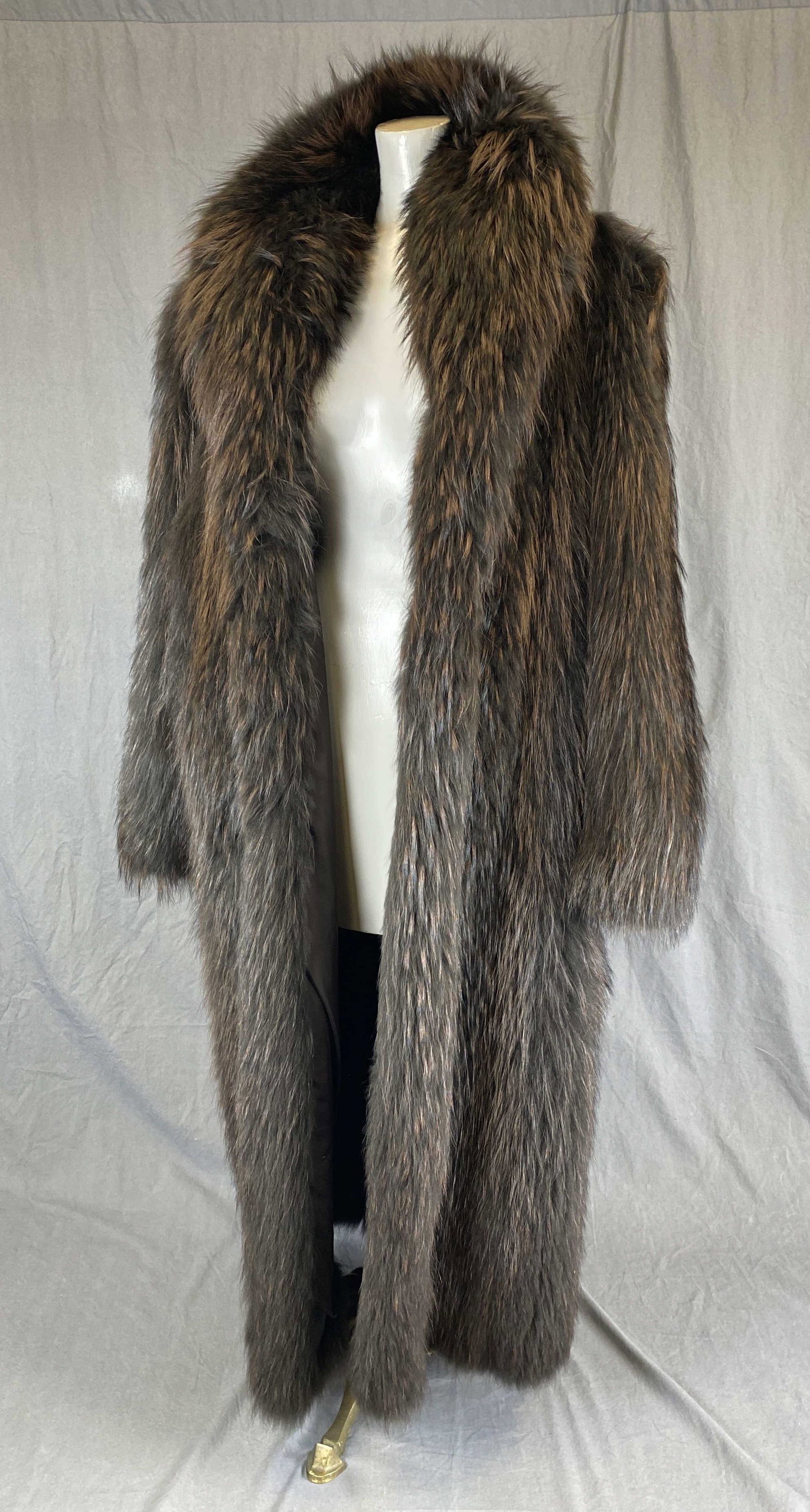 Full Length Chinese Racoon Fur Coat: We were informed by the original owner that this stunning coat is in Chinese racoon fur. The color is very dark brown with lighter reddish brown guard hairs. Dimensions: Labeled a size 10 Chest, armpi