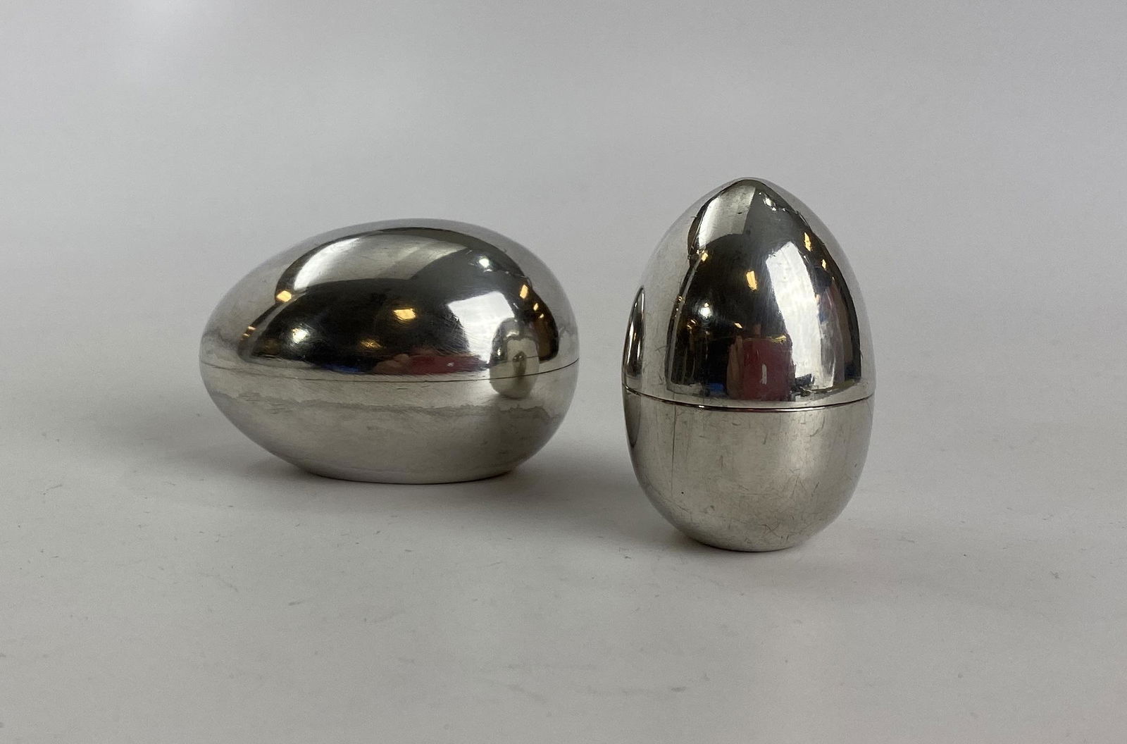 Two Tiffany & Co. Sterling Silver "Egg" Pillboxes: Two egg shaped sterling silver pill or trinket boxes from Tiffany & Co. One is horizontal, the other vertical. The upright egg measures 2" tall, the other measures 2 1/4" long. The total combined weig