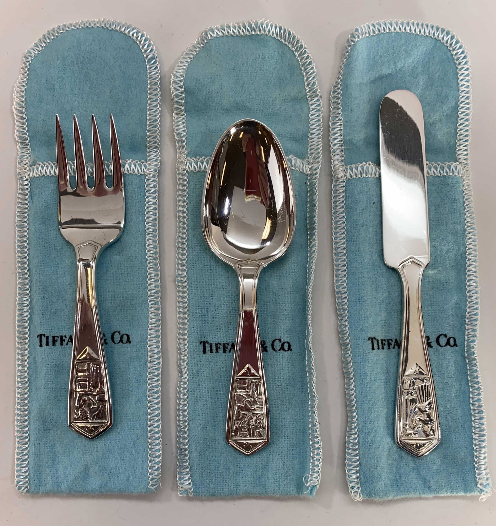 Tiffany & Co. Sterling Old King Cole Child's Set: A 3 piece child's sterling silver flatware set in the Tiffany & Co. Old King Cole pattern. It includes a fork, a spoon and a knife all in their original Tiffany felt holders. The knife measures 5" lon