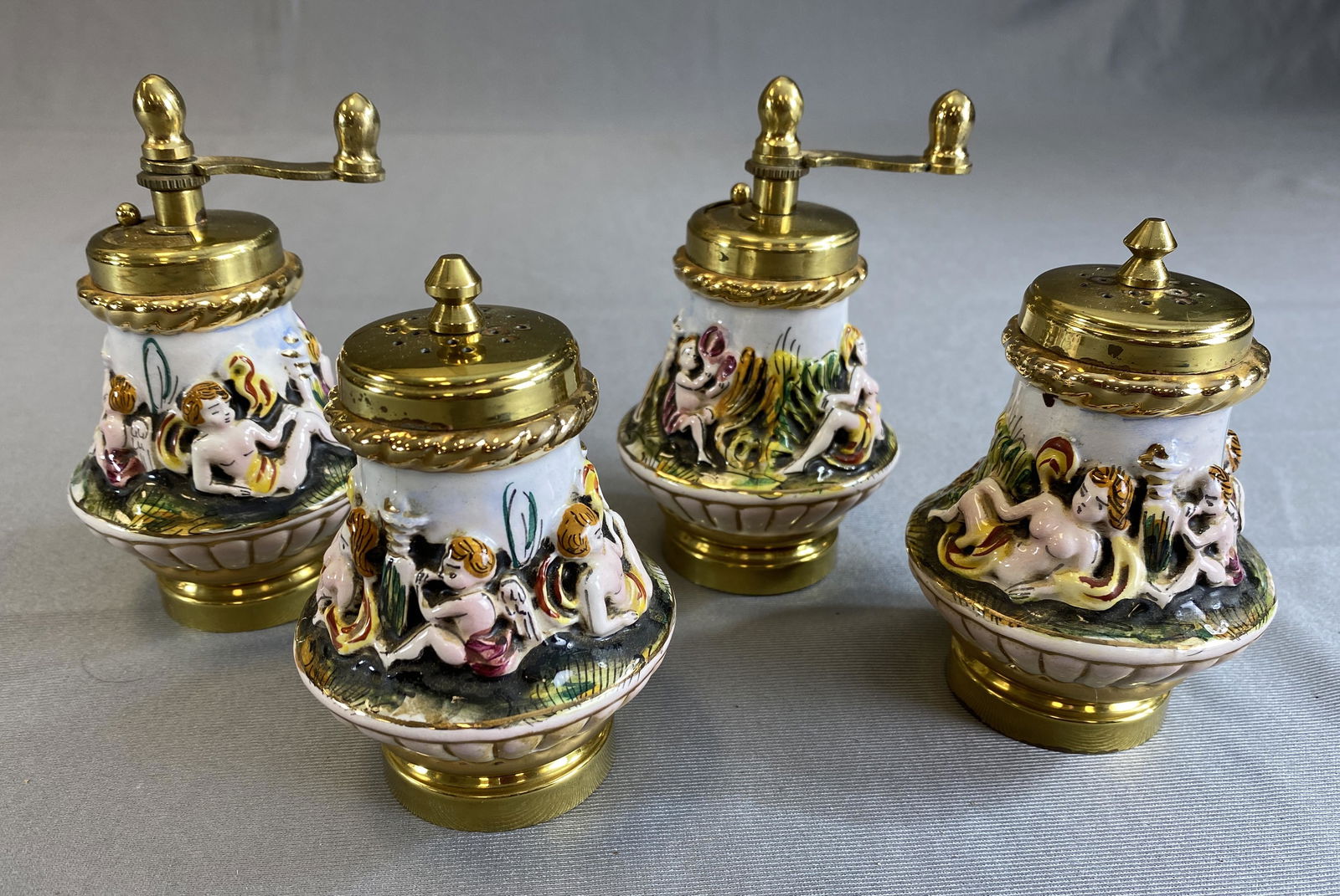 2 Sets Capodimonte Pepper Mills and Salt Shakers: Made in Italy, hand painted with brass fittings. The pepper mills measure 5" tall.