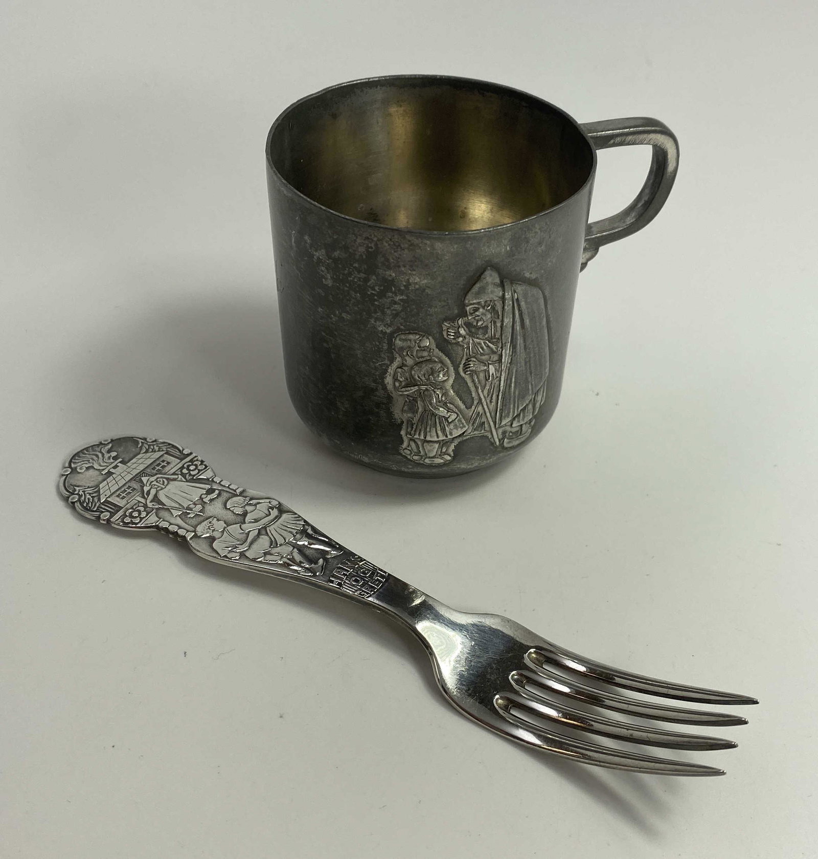 Hansel and Gretel Childs Cup and Fork: The cup appears to be silver plated, its mark is illegible. It measures approximately 2 1/2" tall. The fork is marked 830S as shown.