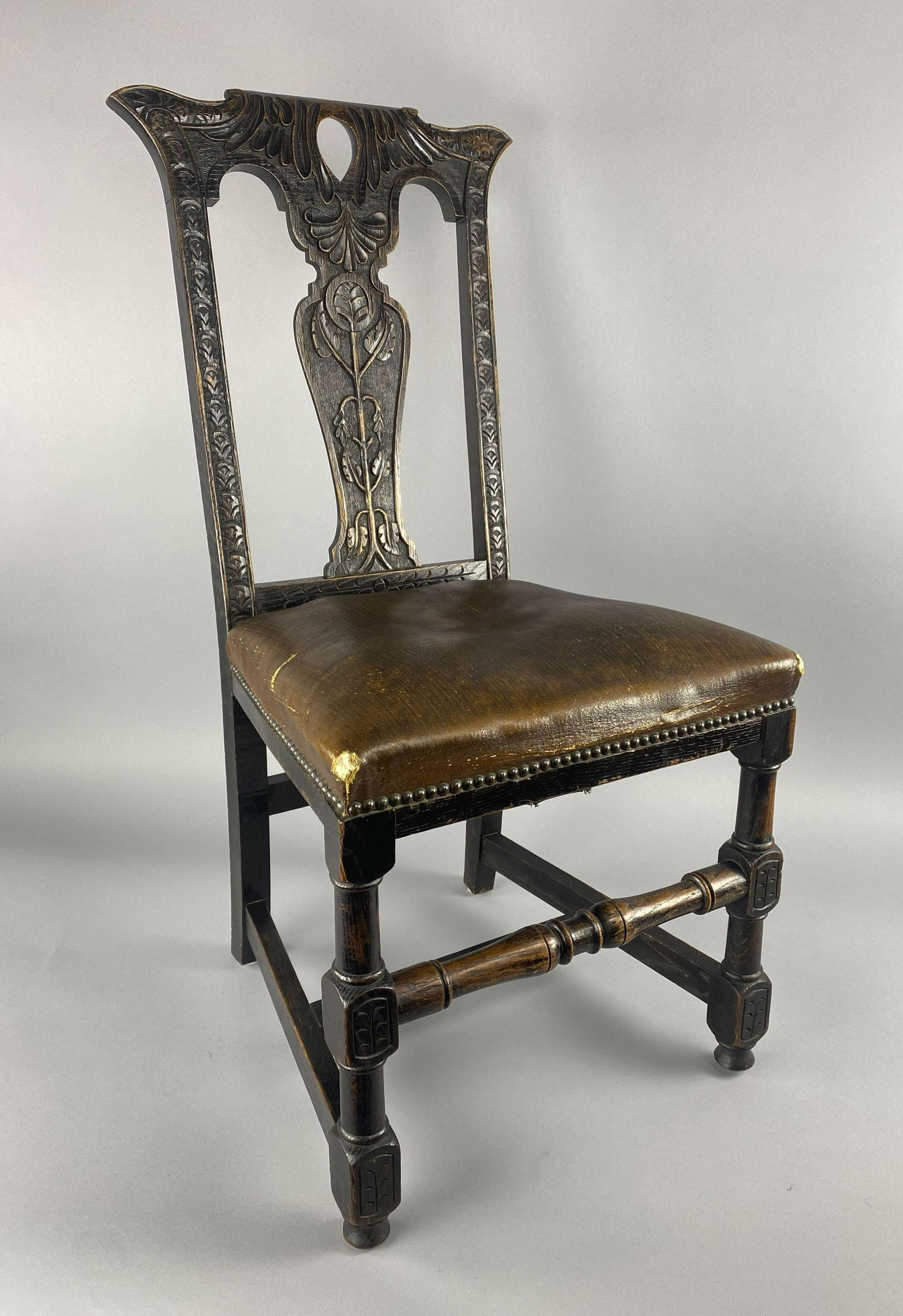Late 19th C. English Carved Oak Hall Chair: English heavily carved oak hall chair with block turned legs. The seat is upholstered in old, possibly original oil cloth leatherette with brass stud trim. Attributed to Hewetson, Milner & Thexton Hei