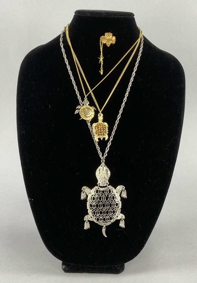 Girl Scout Membership Pin & Turtle Necklaces: 1980's gold tone trefoil membership pin with attached V for five year service and Brownie leader pin. Three necklaces with turtle pendants, one with orange rhinestones, two with articulated parts. SHI