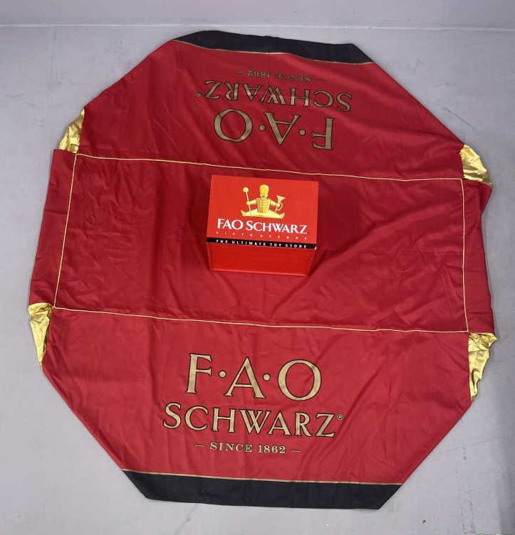 FAO Schwartz Banner and Toy Box: Red and gold double sided FAO Schwarz banner, 87 X 79 1/2 inches in size. Red wooden FAO Schwarz toy box, 17 1/4 X 13 1/4 X 12 inches in size. SHIPPING INFORMATION: In-House Shipping Available