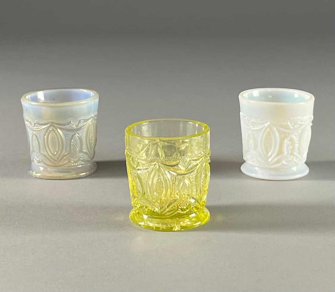3 Miniature 19th C. Sandwich Glass Cups: In a Gothic effect raised design with a stippled background, includes 3 examples - canary yellow, opalescent white and iridescent blue. Each measures 1-3/4" tall. Also includes a fragment excavated at