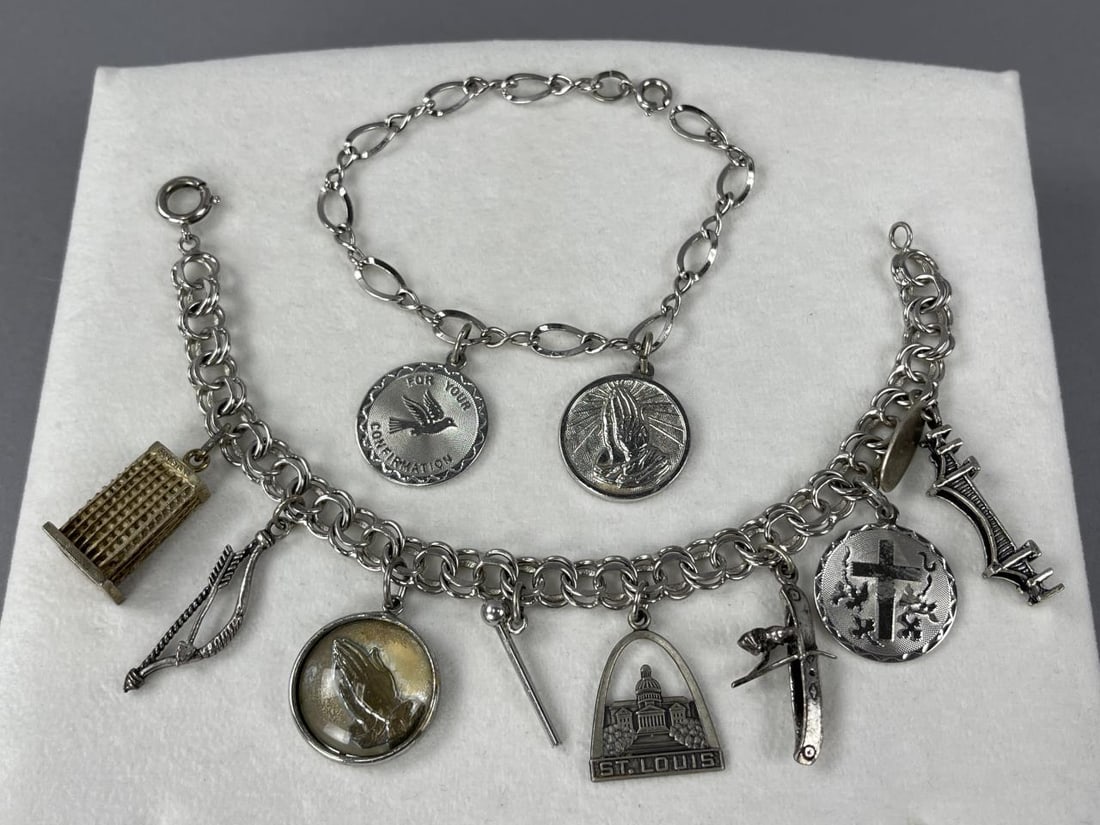 2 Sterling Silver Charm Bracelets with Charms: Confirmation charm, Serenity Prayer charm on 7'' bracelet marked Sterling, 10.48 grams total weight.7 1/4'' charm bracelet marked Sterling, with bow & arrow, cross, Mackinac Bridge, Indian canoe, Fore