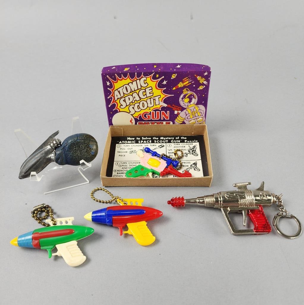 Space Gun Key Chains and Rubber Bulb Squirt Gun: 4'' mini cap gun on key chain, marked Galaxy.Atomic Space Scout Gun Puzzle and Key Chain with box made by Champion Plastics Corp. circa 1952.2 vintage space gun puzzle toys, unbranded, 3'' x 1.5''.Vin