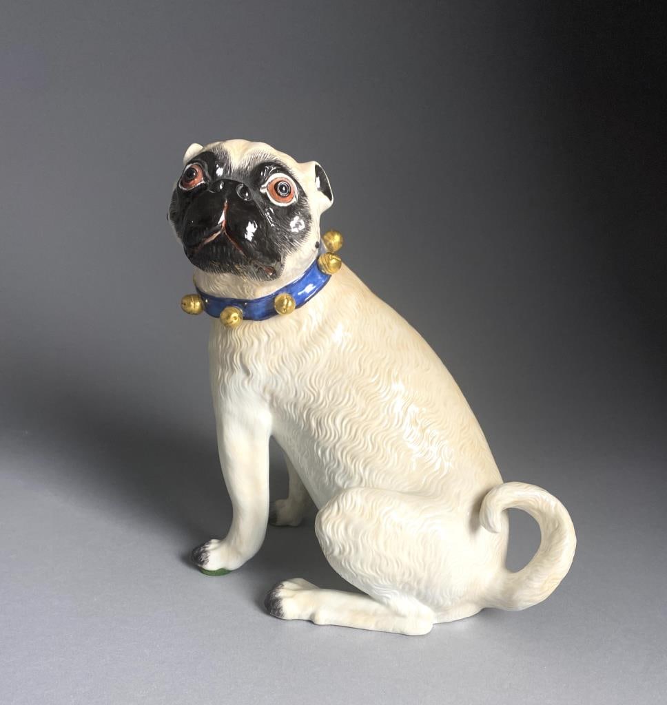 Meissen Porcelain Figure of a Seated Pug Dog 9": Meissen porcelain figure of a seated pug dog wearing a blue collar with gold painted bells, marked on underside with the underglaze blue crossed swords mark, impressed "78579", "29E", and a gold foil 