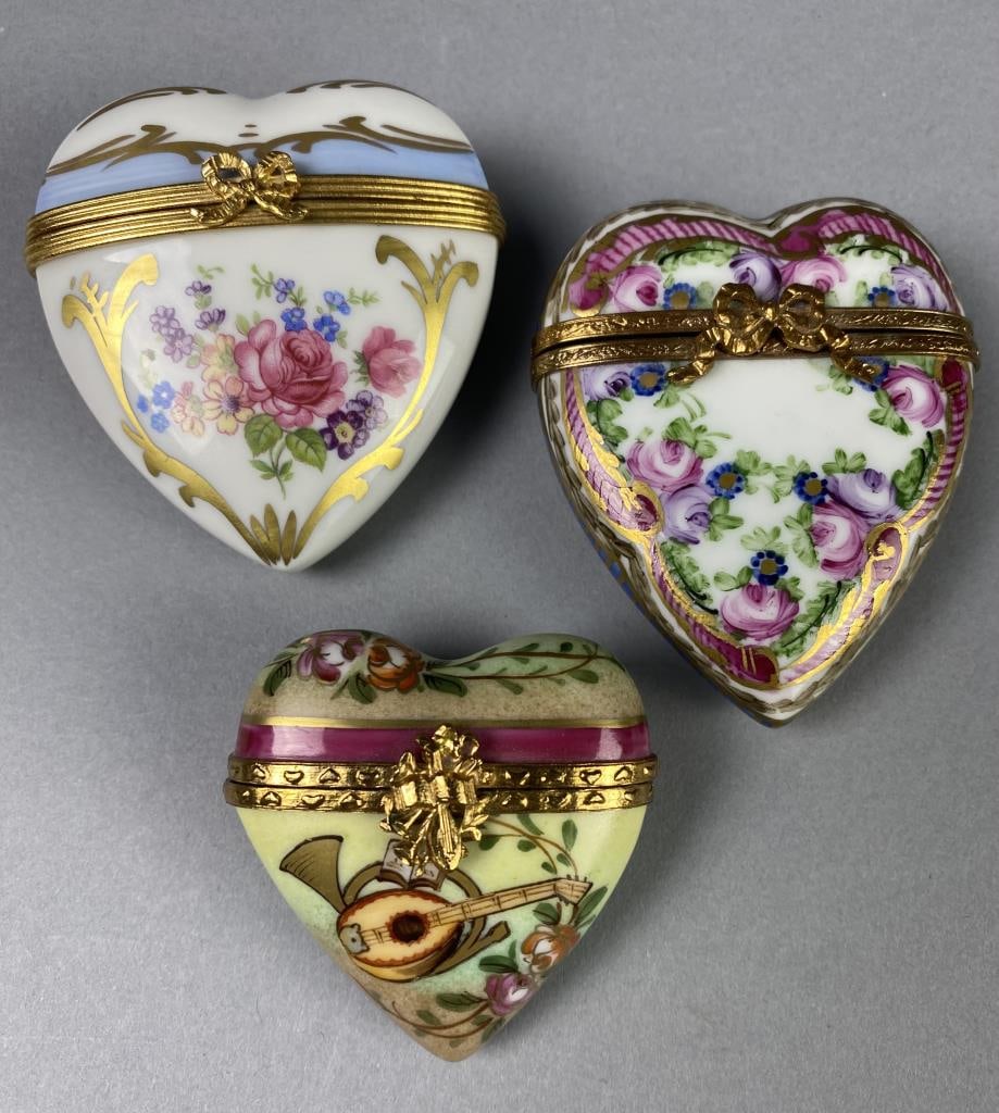3 Limoges Heart Shaped Hinged Trinket Boxes: Limoges, France porcelain hinged heart shaped boxes, two with floral motif, 2-3/4" L x 2-1/2" W and 2-3/4" L x 2-1/4" W, and one with music or musician theme, 2-1/8" L x 2" W, all have hinges and open