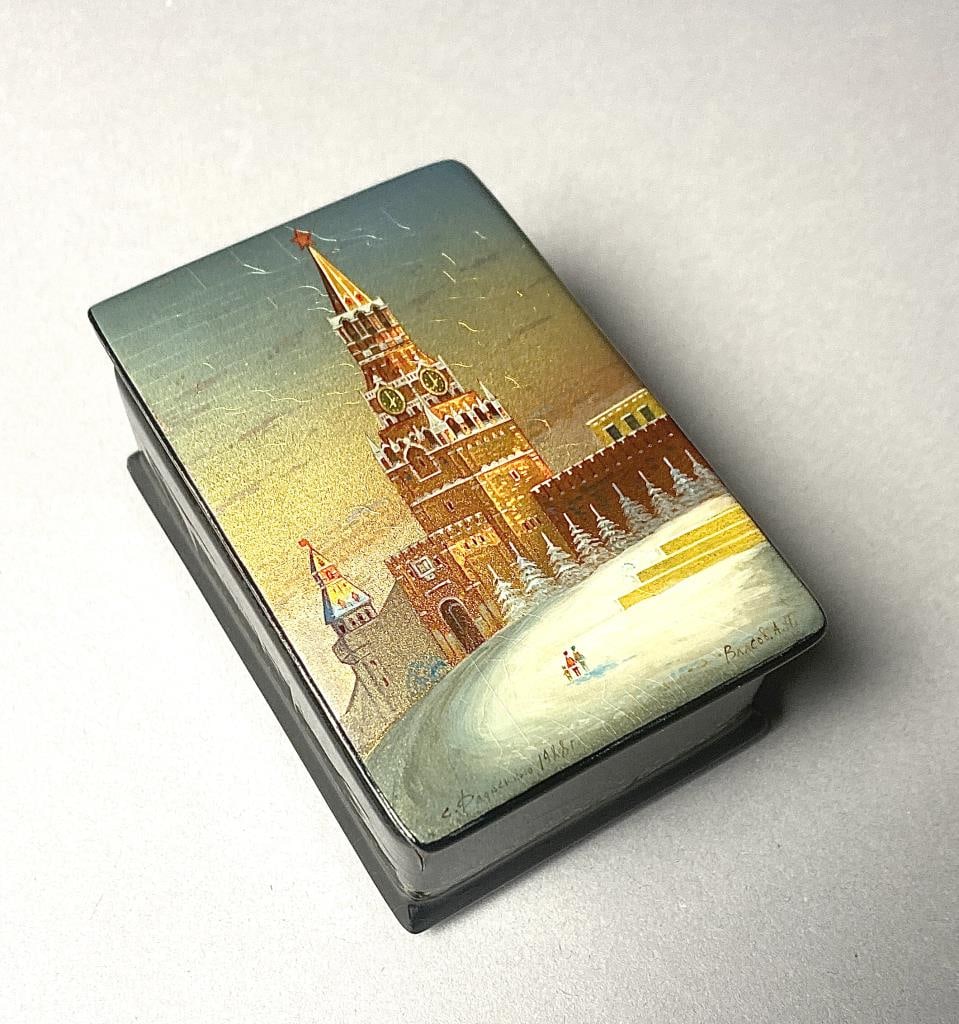 Russian Fedoskino Lacquer Box Spasskaya Bashnya: Russian hinged lidded, black lacquer, hand painted Fedoskino box, with red interior, gilt gold accents, and depicting the Spasskaya Bashnya, also known as the Saviour Tower, which is the main tower on