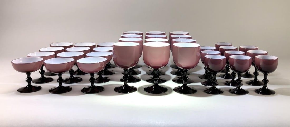 34 Carlo Moretti Amethyst Case Glass Goblets: Collection of amethyst, or purple, case glass goblets with white interiors. The set includes: (12) 5-3/4" water or wine glasses; (12) 3-3/4" champagne or sherbet glasses; and (10) 4-1/2" cordial glass