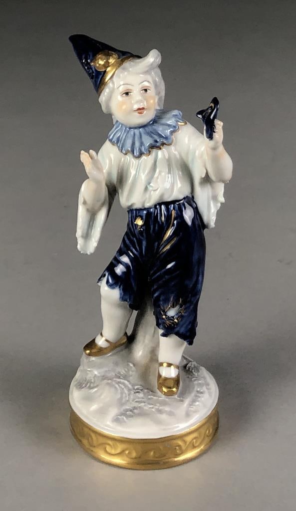 Volkstedter Porcelain Pierrot Boy Figurine: Hand painted porcelain figure, depicting a boy wearing a pierrot costume and holding a theatre mask, by the Aelteste Volkstedter Porzellanfabrik, circa mid 20th Century, marked on bottom with the blue