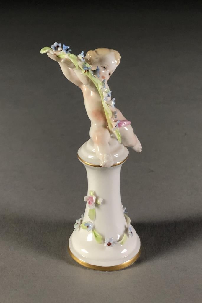 Capodimonte Cherub Figure on Pedestal: Capodimonte cherub, or putto, figure with floral garland on a pedestal, marked on bottom, approximately 4-3/8" in height. SHIPPING: In-House S