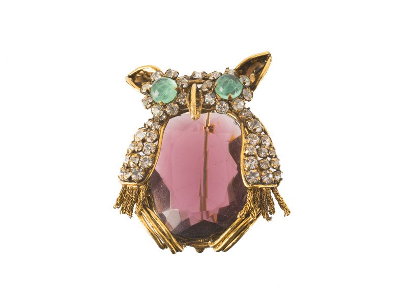 An Iradj Moini goldtone brooch depicting an owl, set: An Iradj Moini goldtone brooch depicting an owl, set with purple and green stones and rhinestones. Signed Iradj Moini. L. 5 cm.